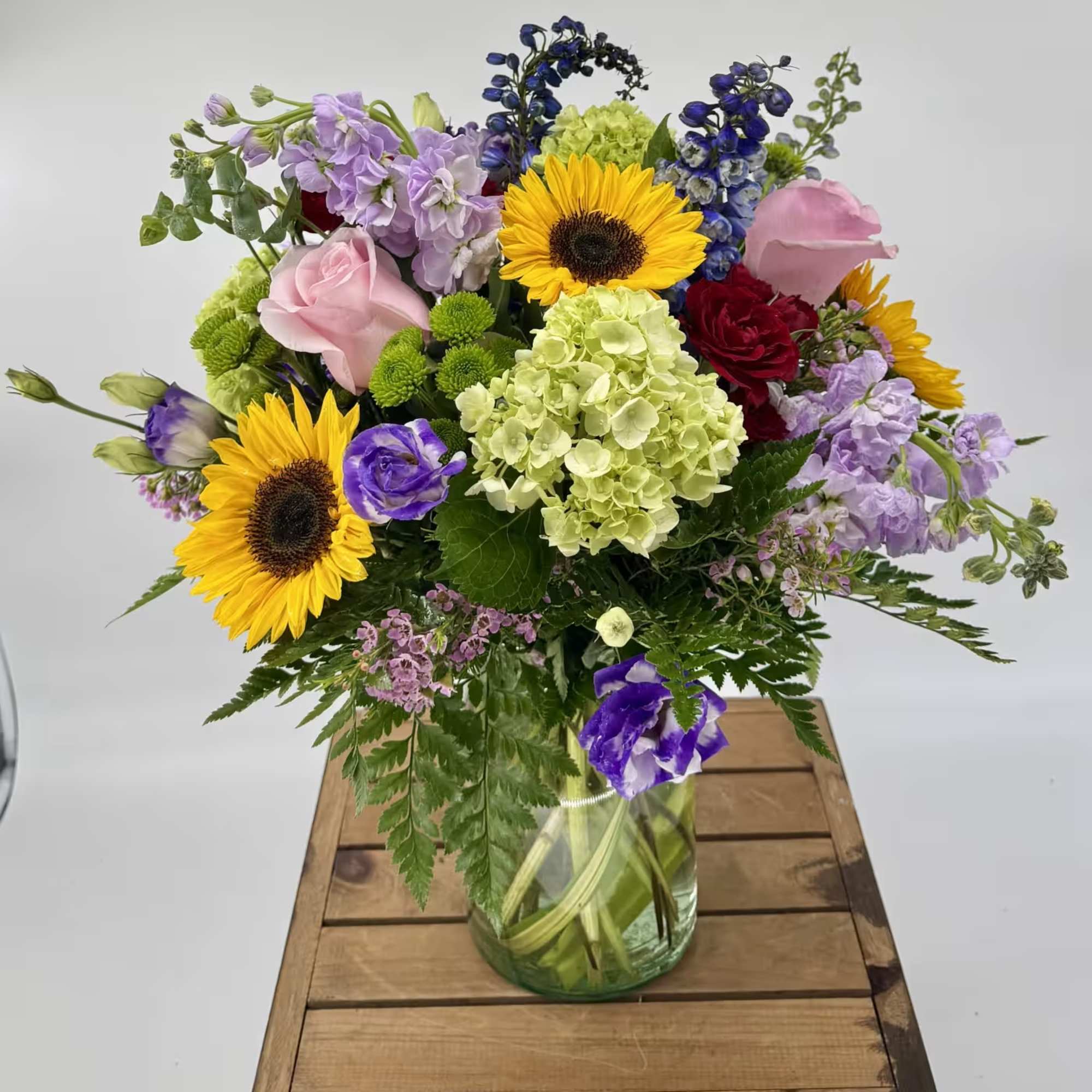 Mixed bouquet in a glass vase with sunflowers, roses, and hydrangea