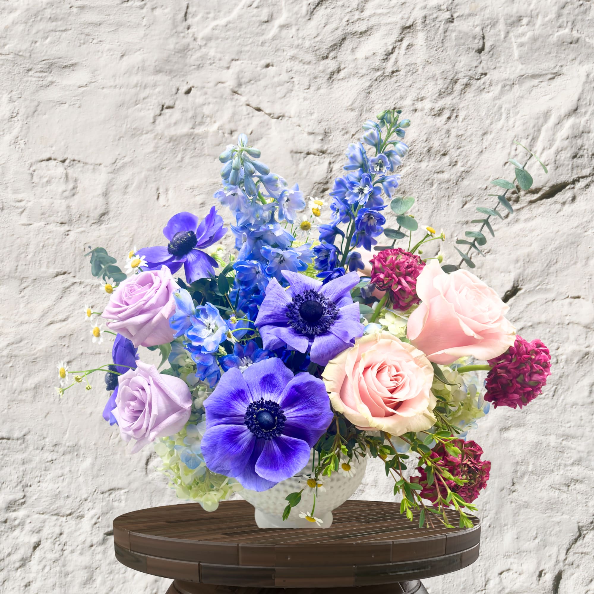 Bouquet of purple, pink, and blue flowers in a white vase