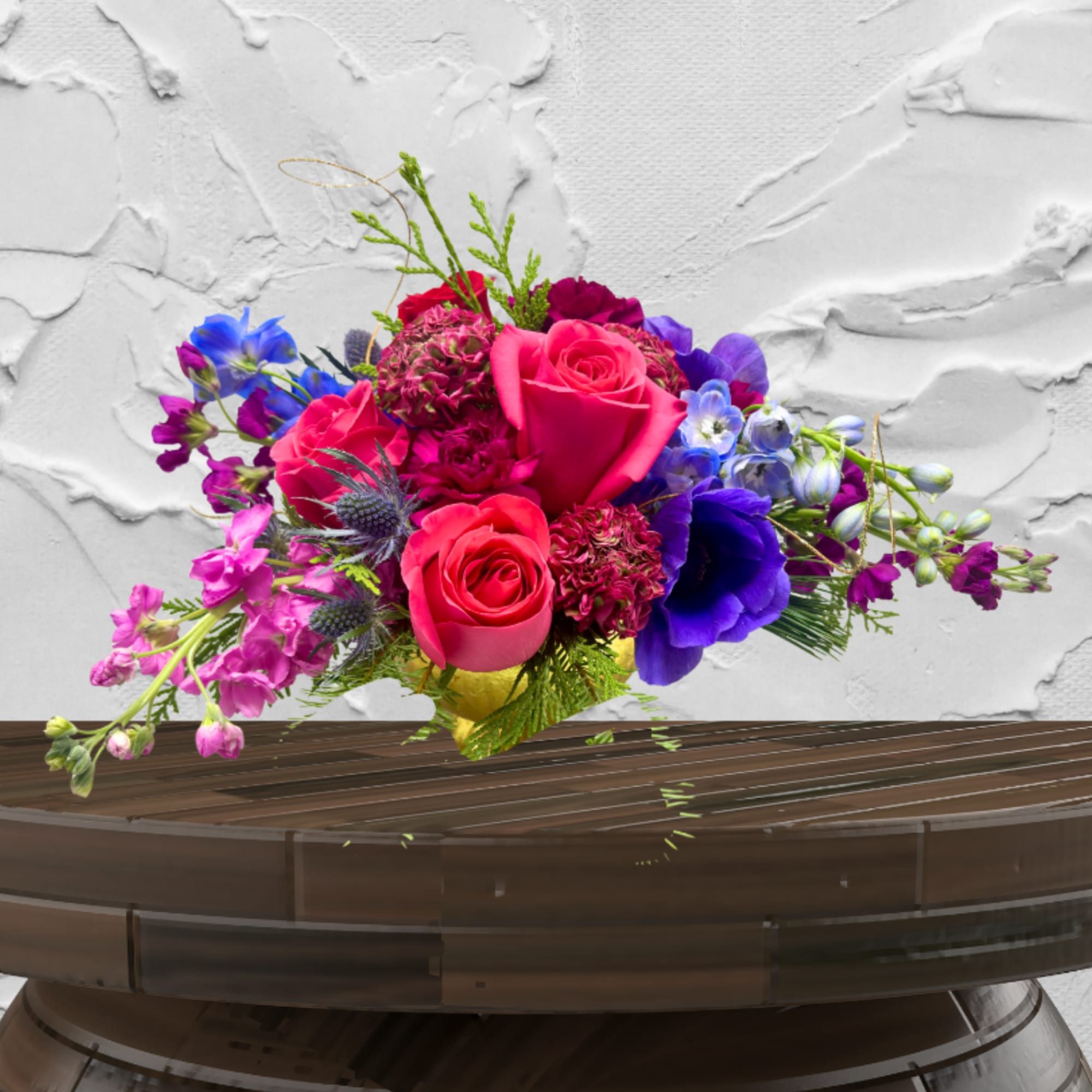 Bright mixed bouquet with pink roses and purple flowers in a low container