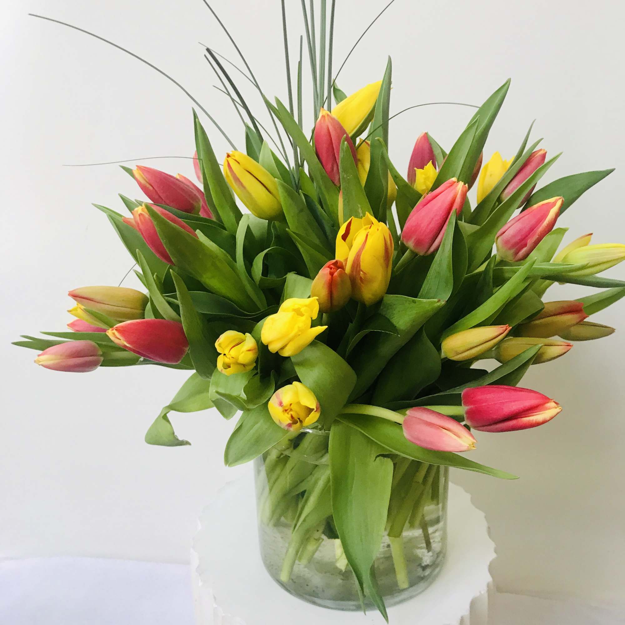 50 stems of different colors of tulips.in clear glass vase arranged by