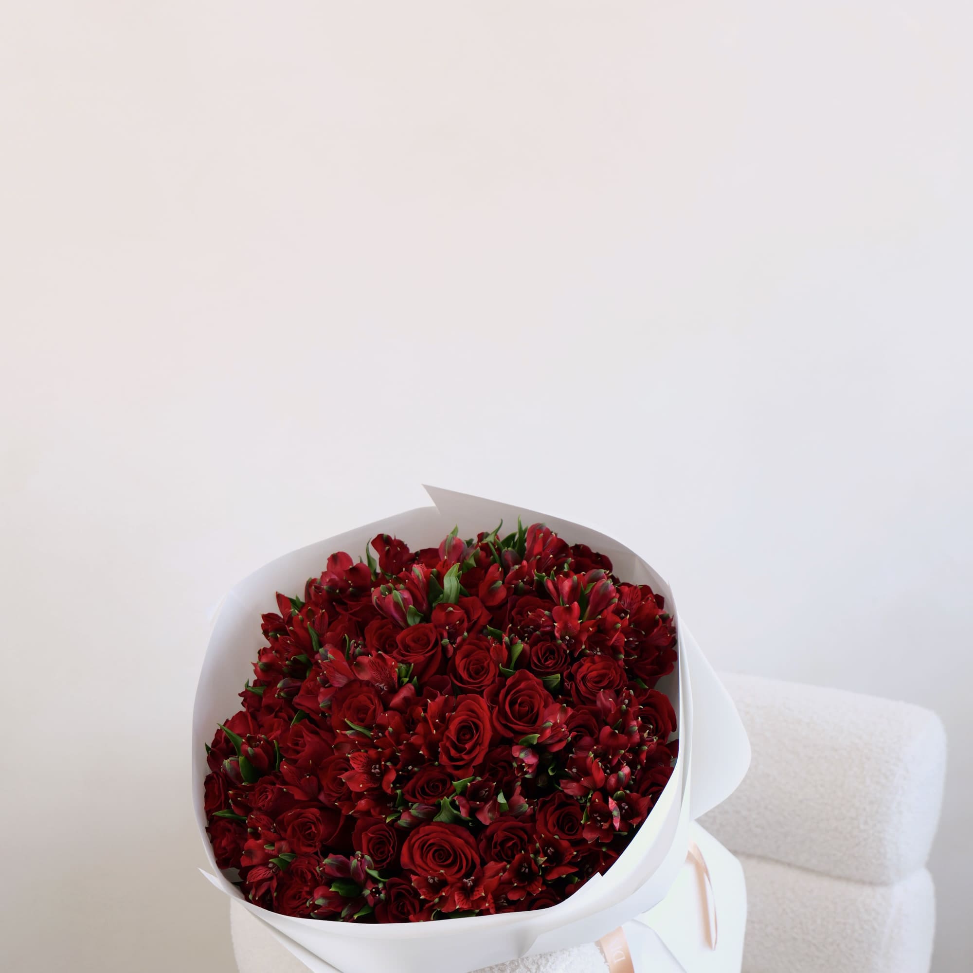 A beautiful bouquet featuring red roses and alstroemeria, carefully arranged and wrapped