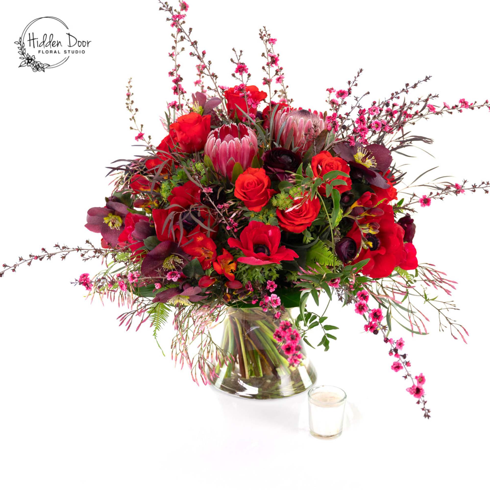 Merlin
Some arrangements whisper. Merlin commands the room. Deep crimson, burgundy, and dramatic