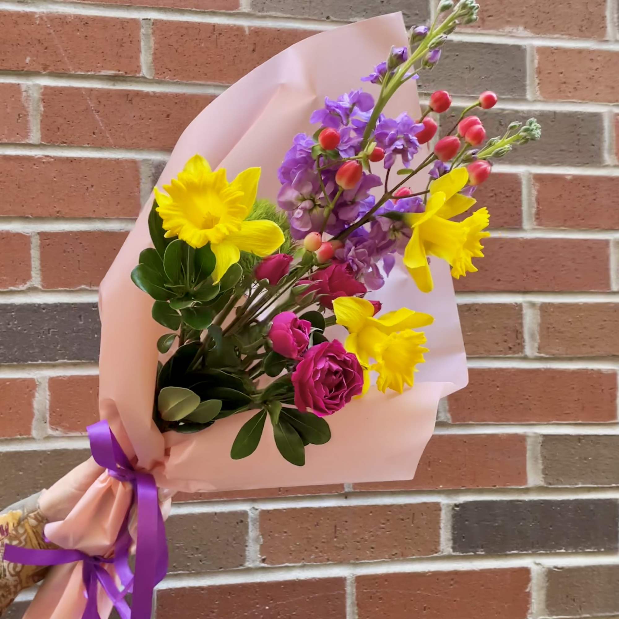 'Into The Hills' is a wrap bouquet of Daffodils, Stock, spray Roses