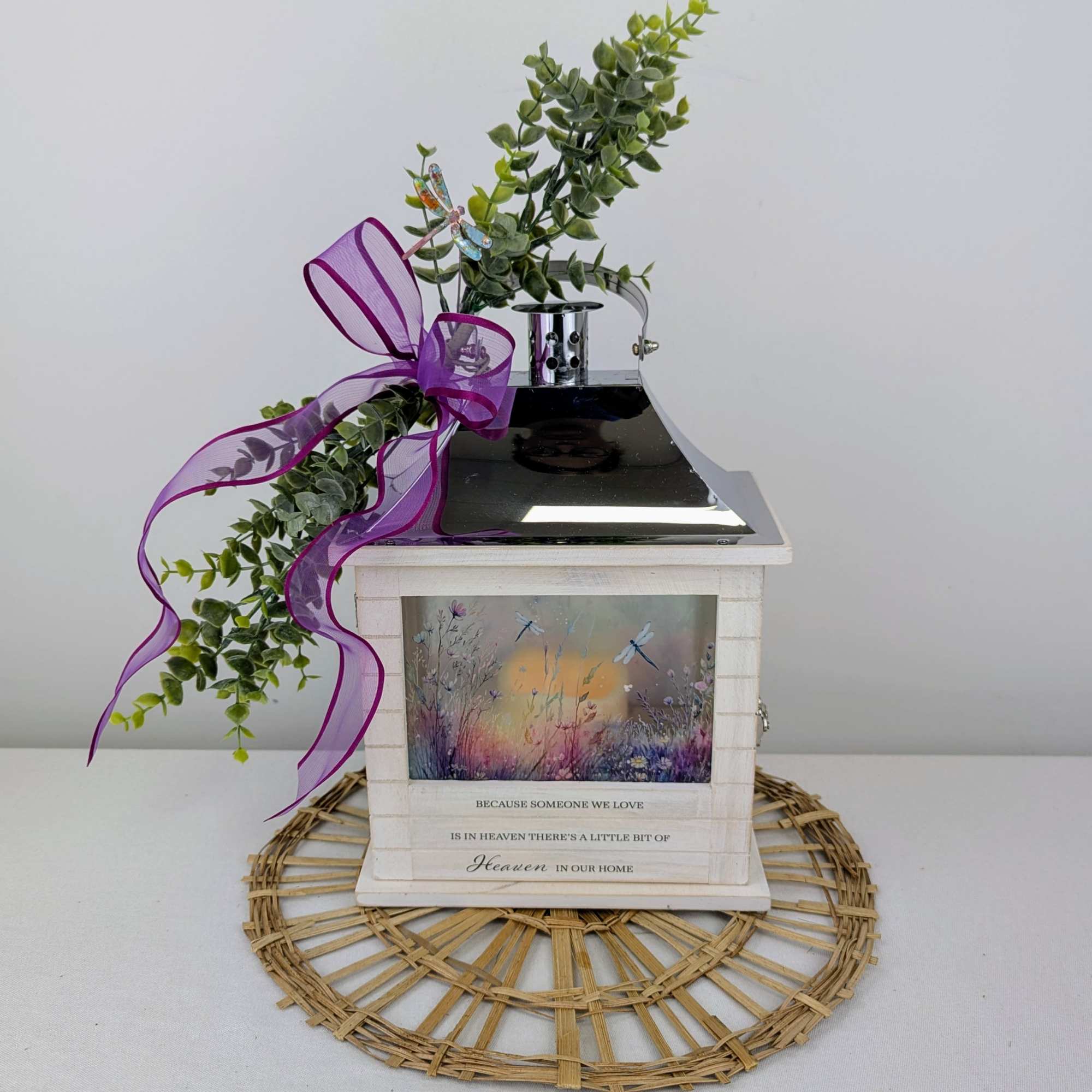 Decorative memorial lantern with greenery and a purple ribbon