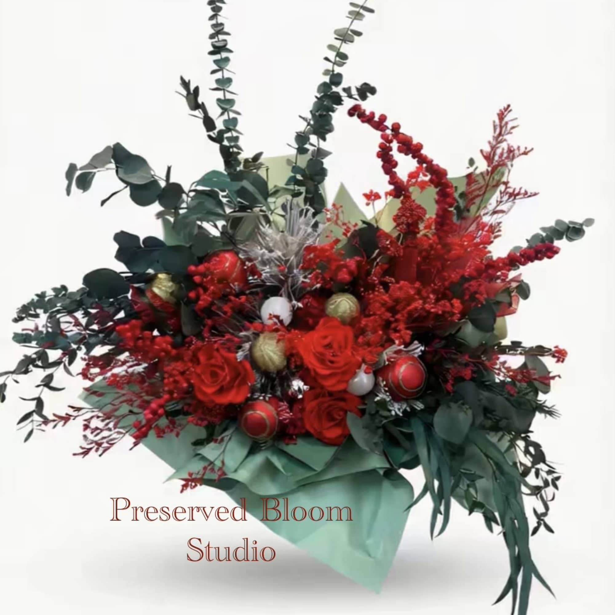 This is a Christmas-themed basket, mainly composed of red roses, eucalyptus leaves