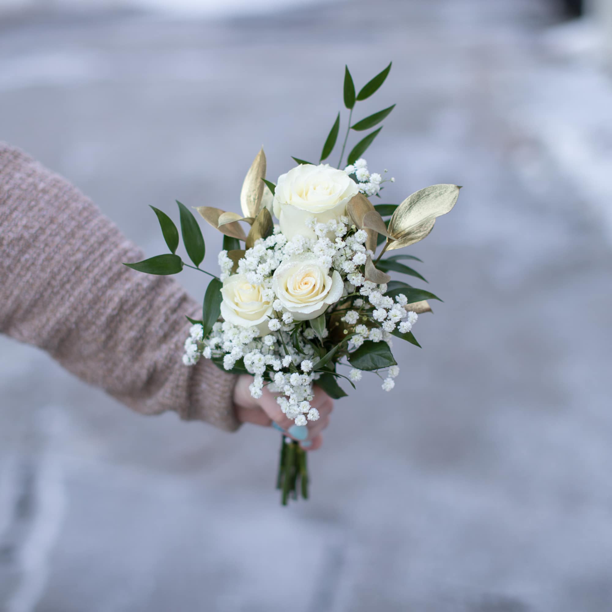 Small bouquet of white roses and baby's breath with green leaves