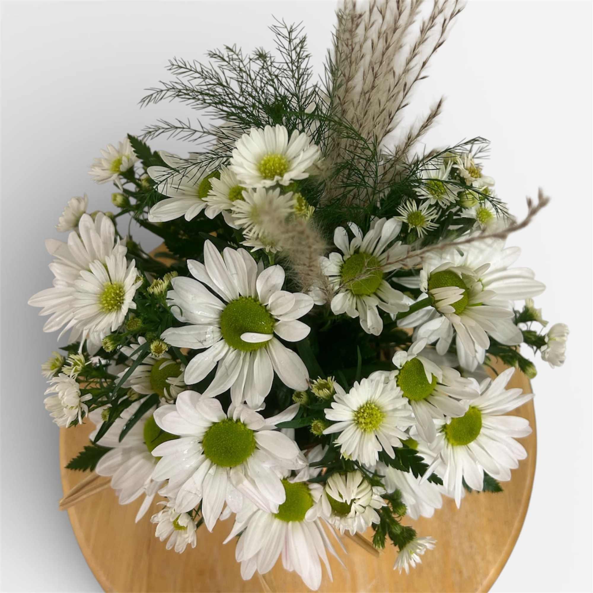 A daisy arrangement accented with a pampas grass plume designed in a