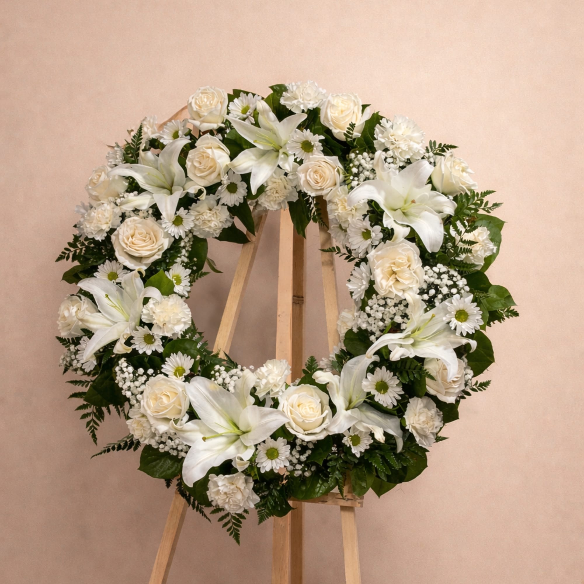 A classic sympathy wreath of white roses, lilies, chrysanthemums , and baby&rsquo;s