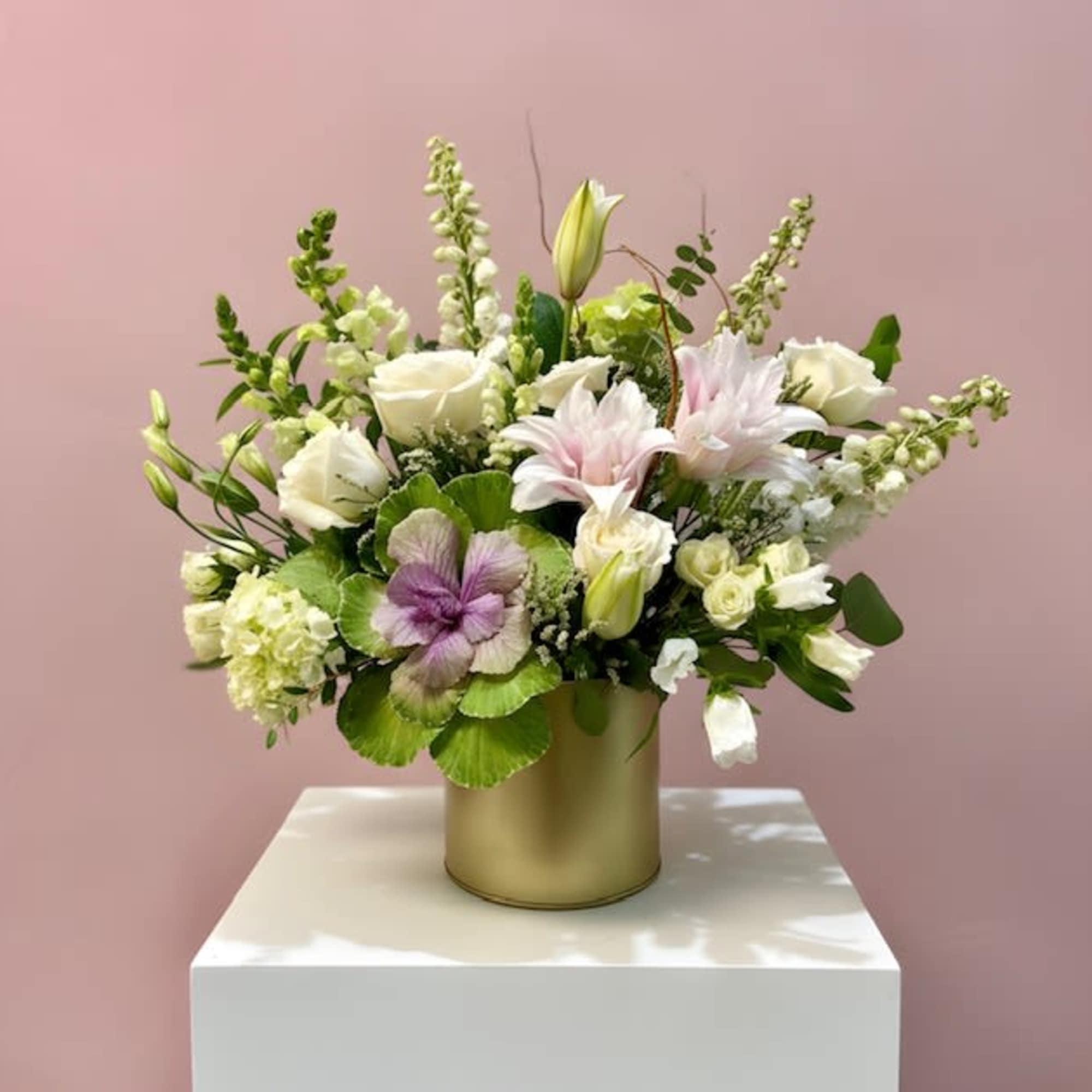 An elegant white and green arrangement featuring textured kale, white roses, delphinium