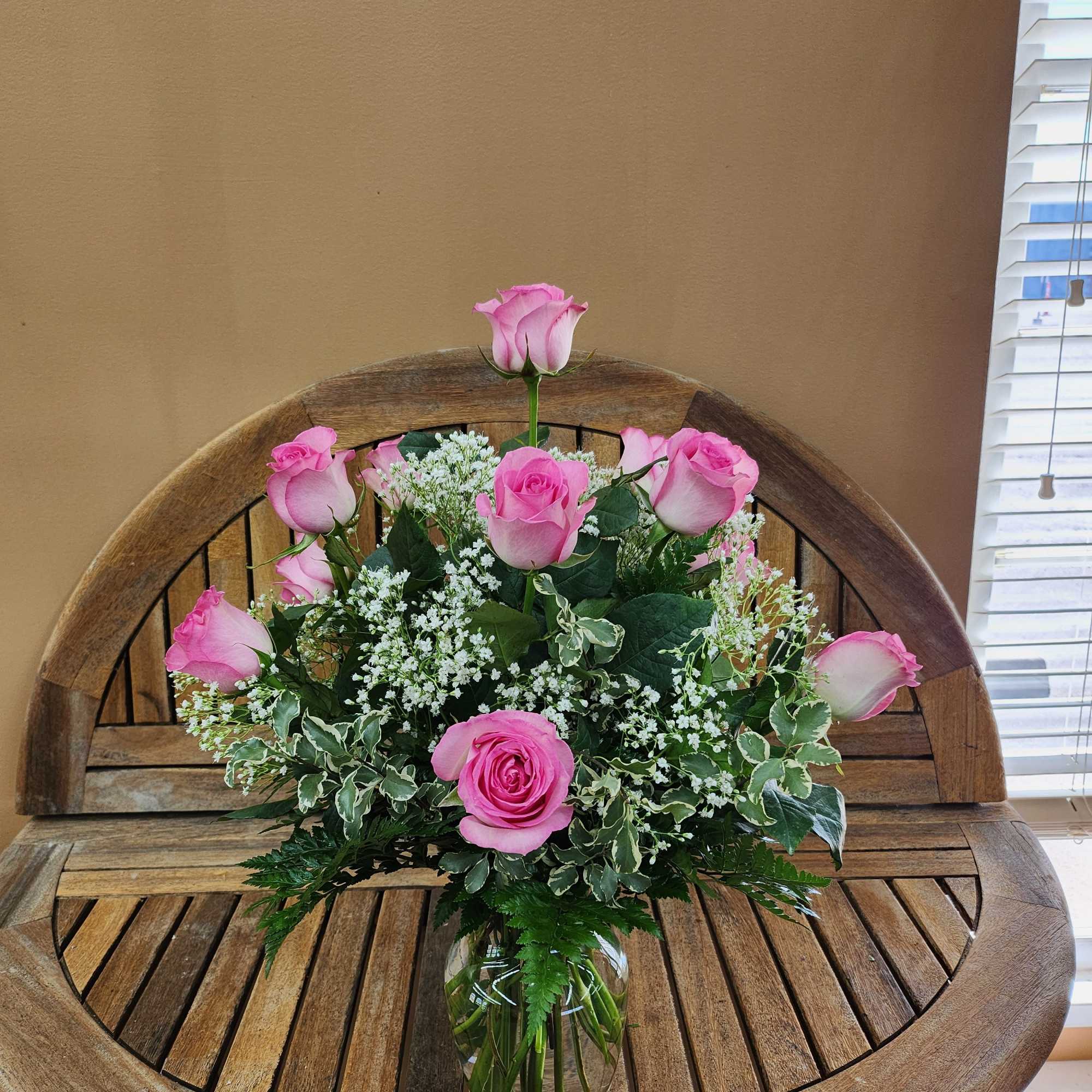 Pink rose in clear vase with greenery and highlighted with filler Flowers