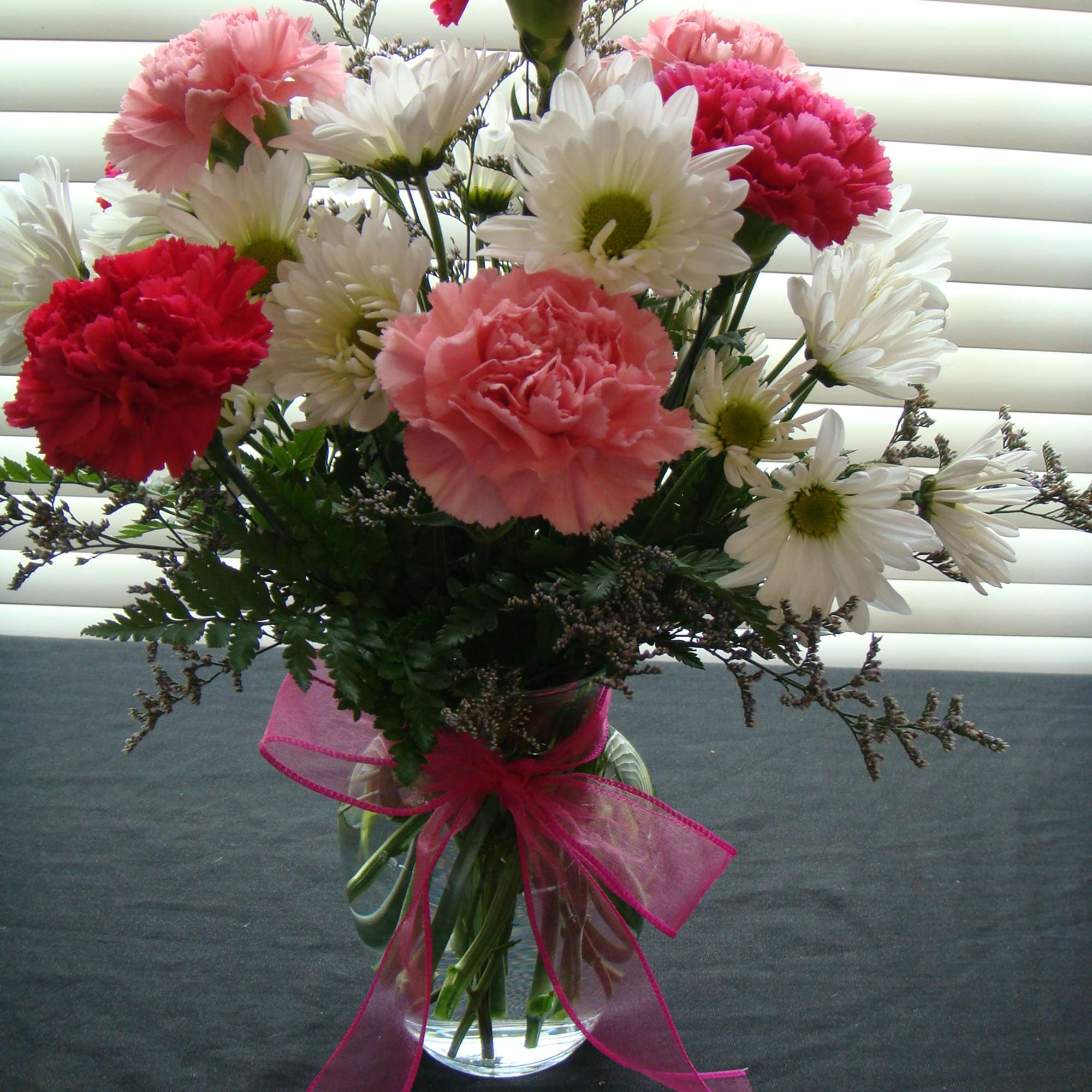 Bouquet of pink carnations and white daisies in a glass vase