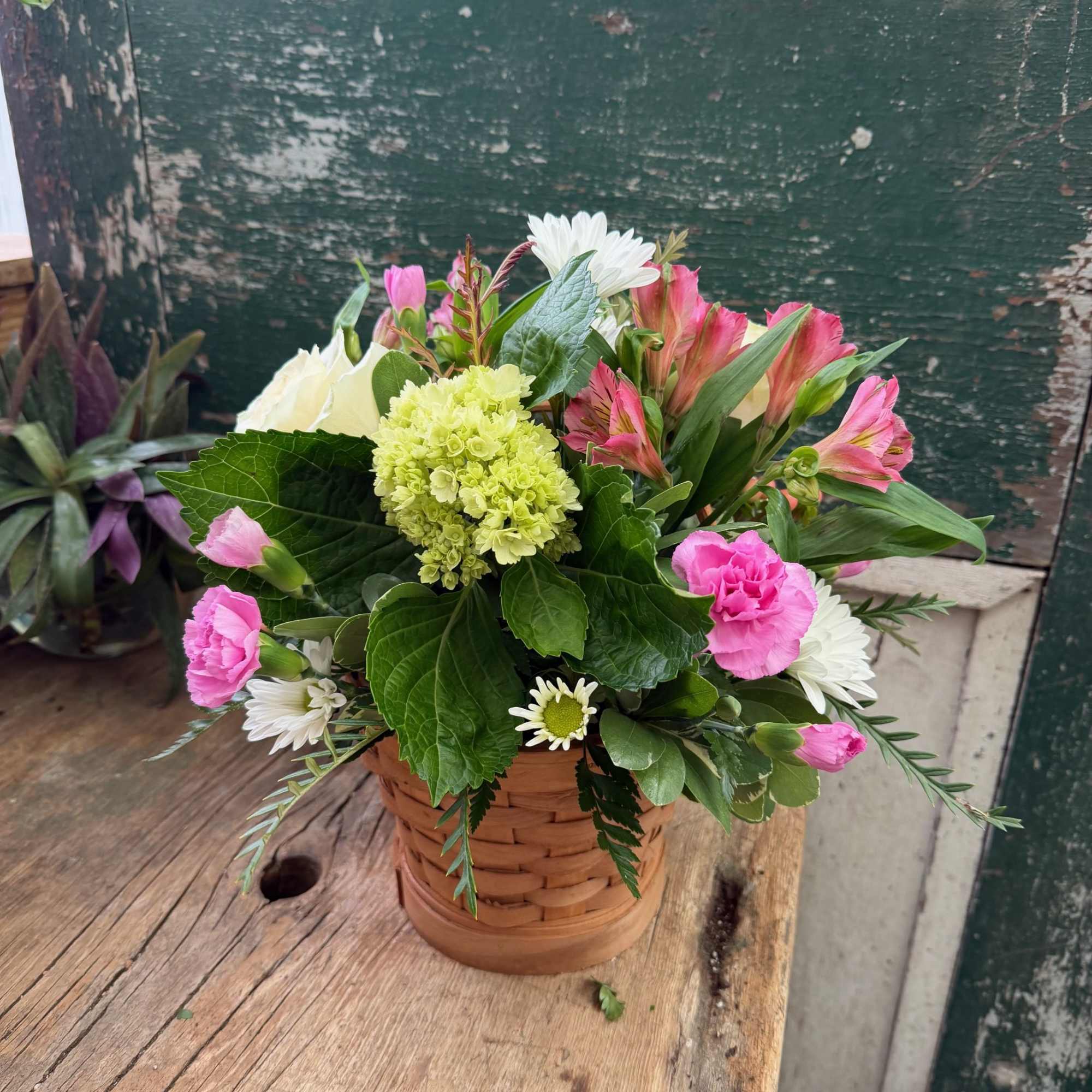Mixed pink and white flowers in a woven basket container