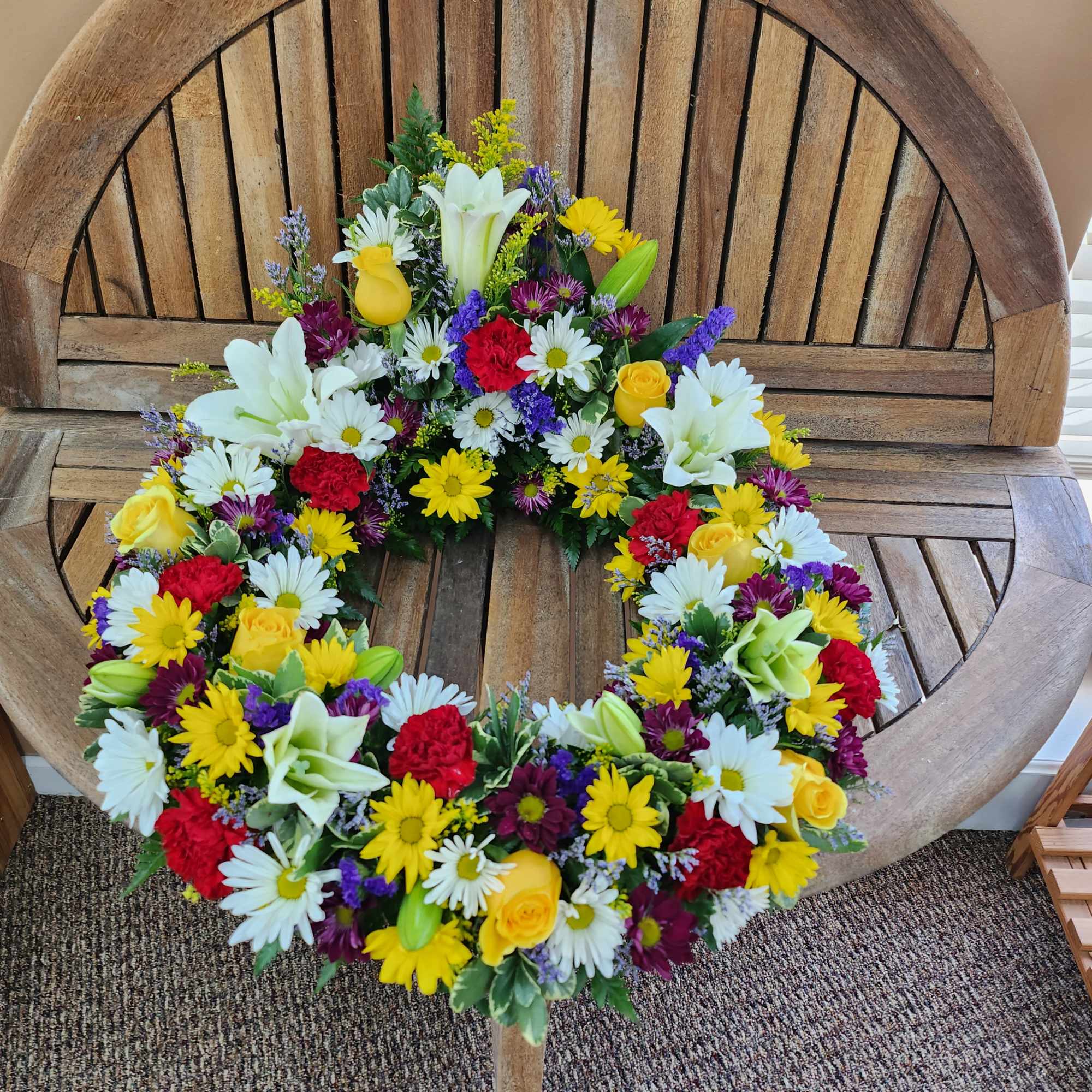 Colorful floral wreath with daisies, roses, lilies, and carnations