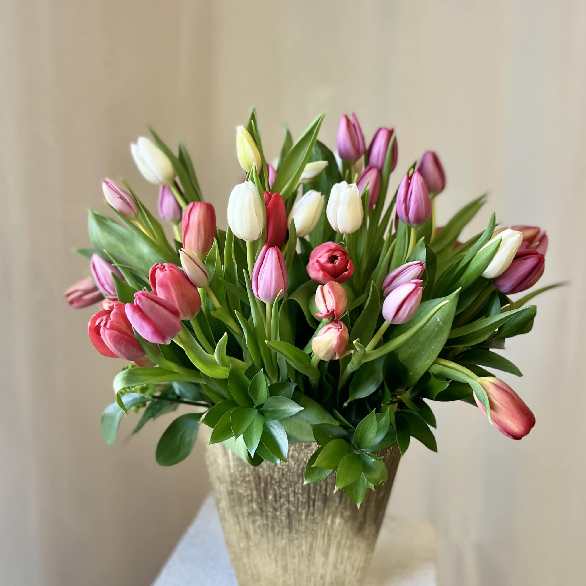 Bouquet of pink, white, and red tulips in a gold vase