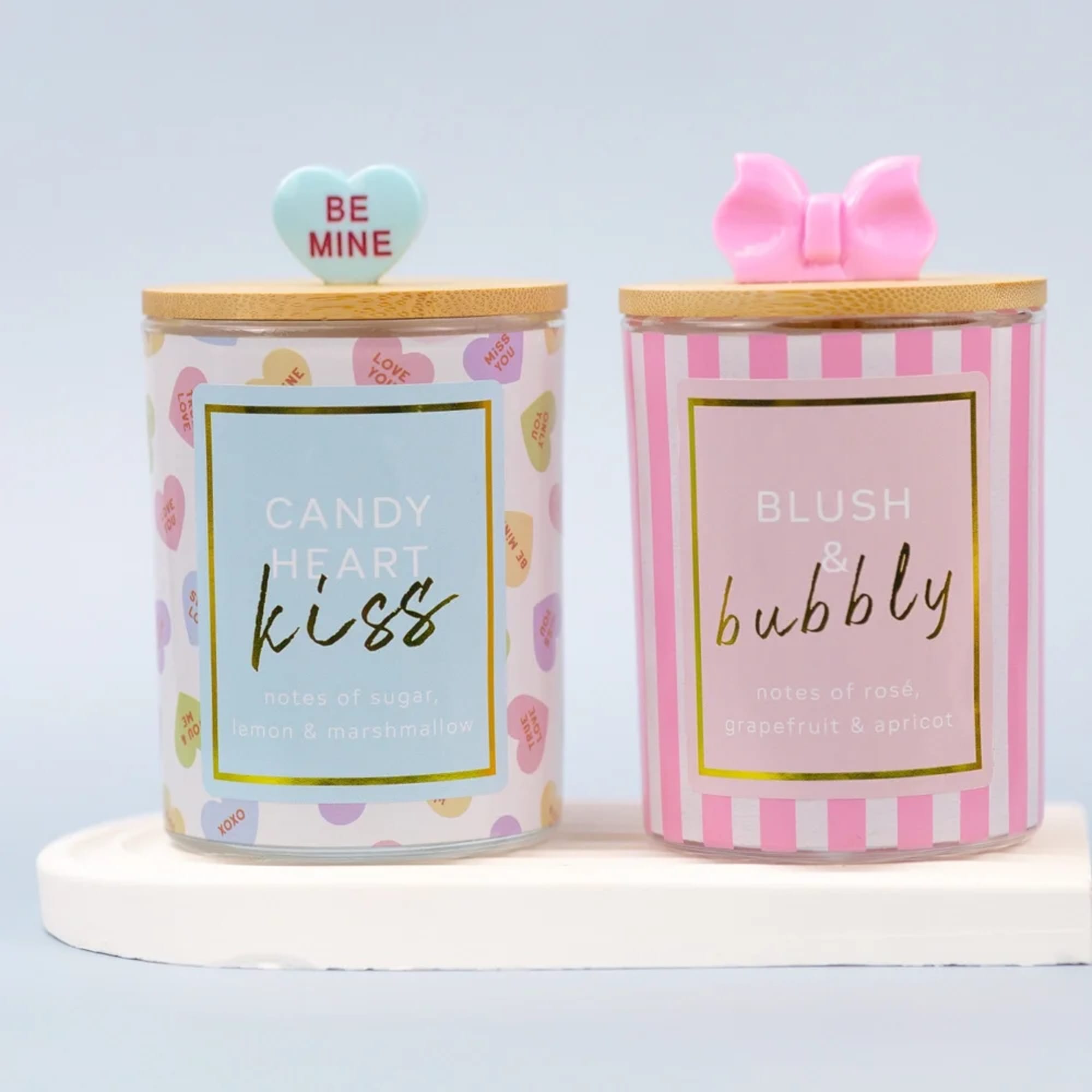 Two decorative candles in glass jars with heart and bow lids