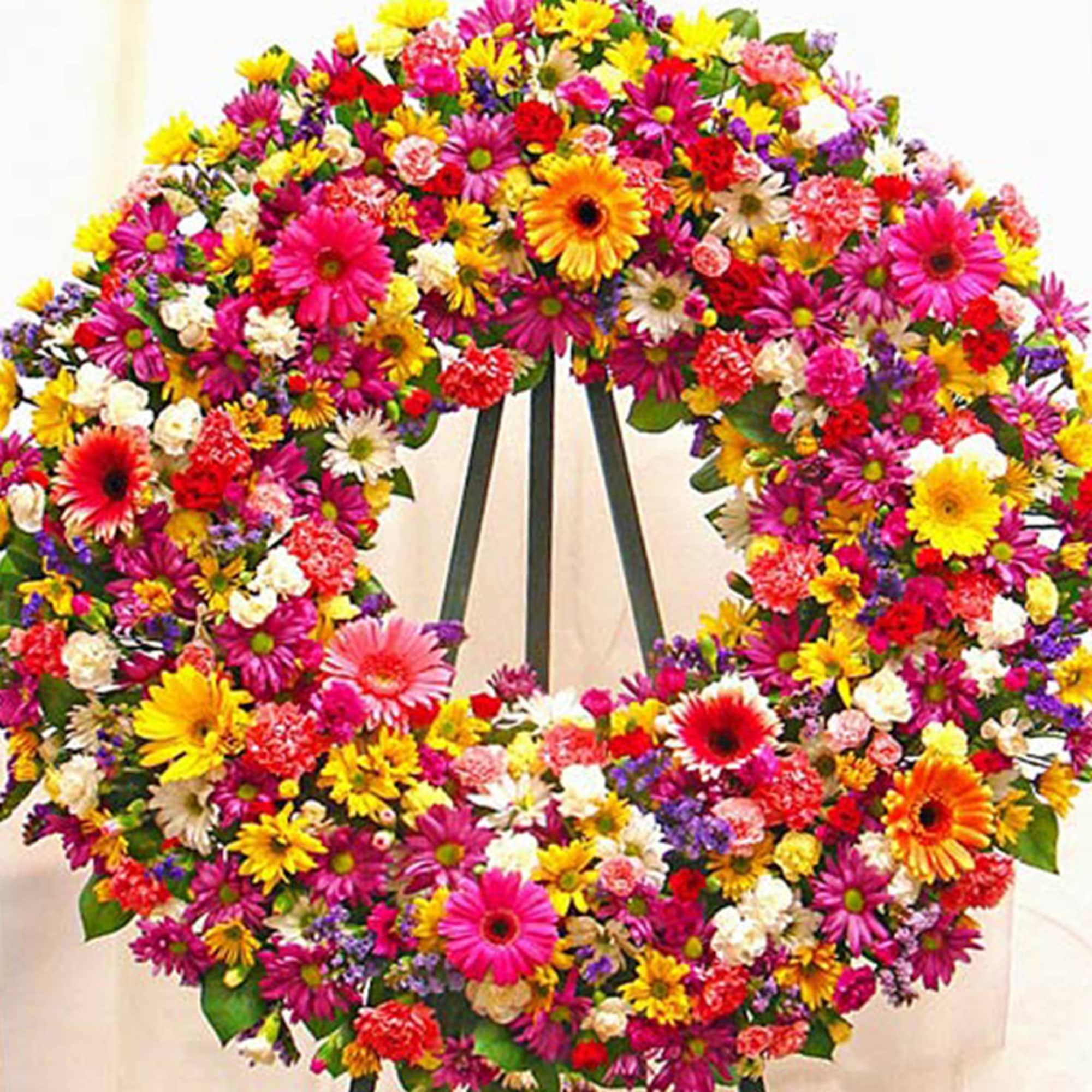 Large standing wreath of bright mixed flowers in pink, yellow, white, and purple on an easel