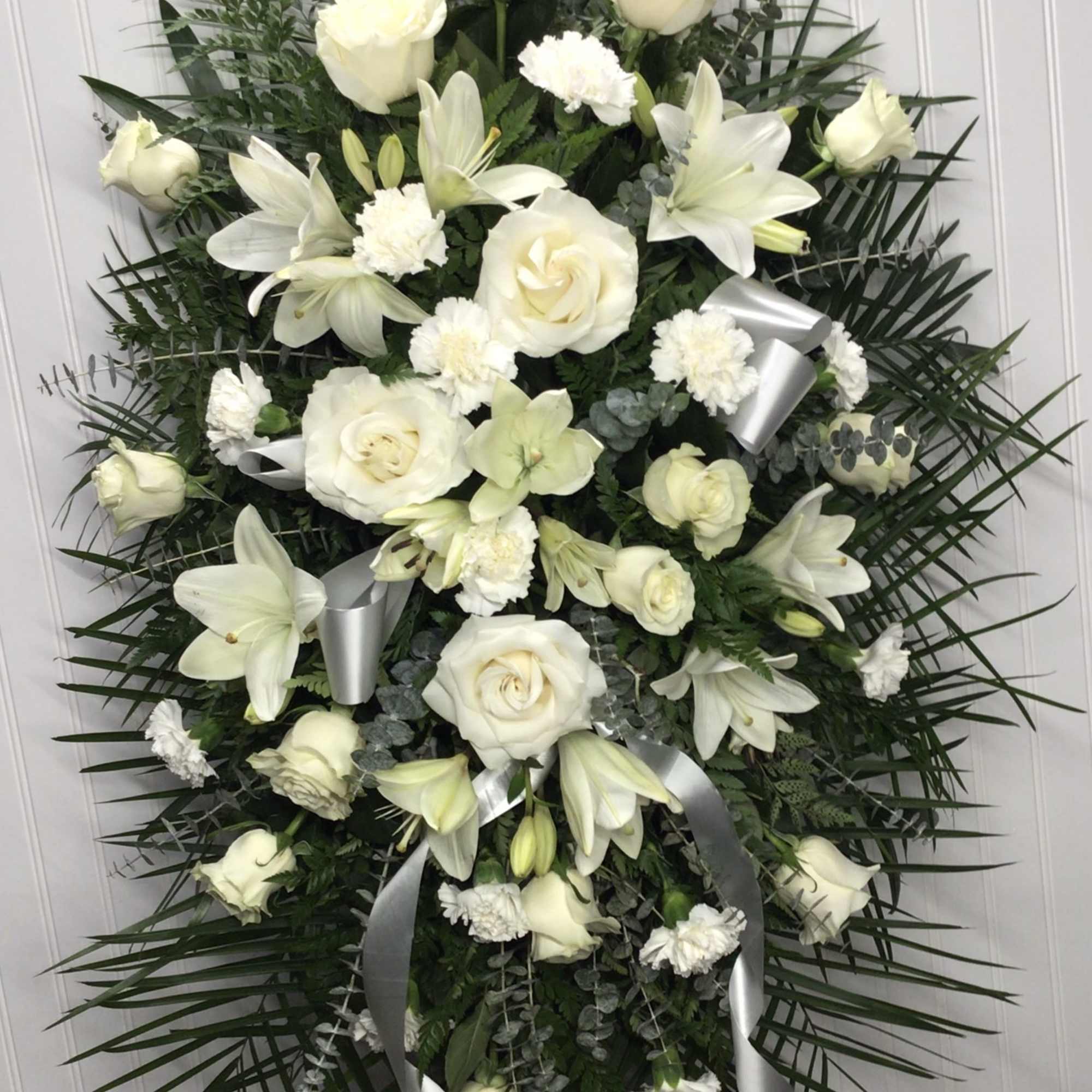 Beautifully simple this lovely spray of white roses lilies and carnations decorated