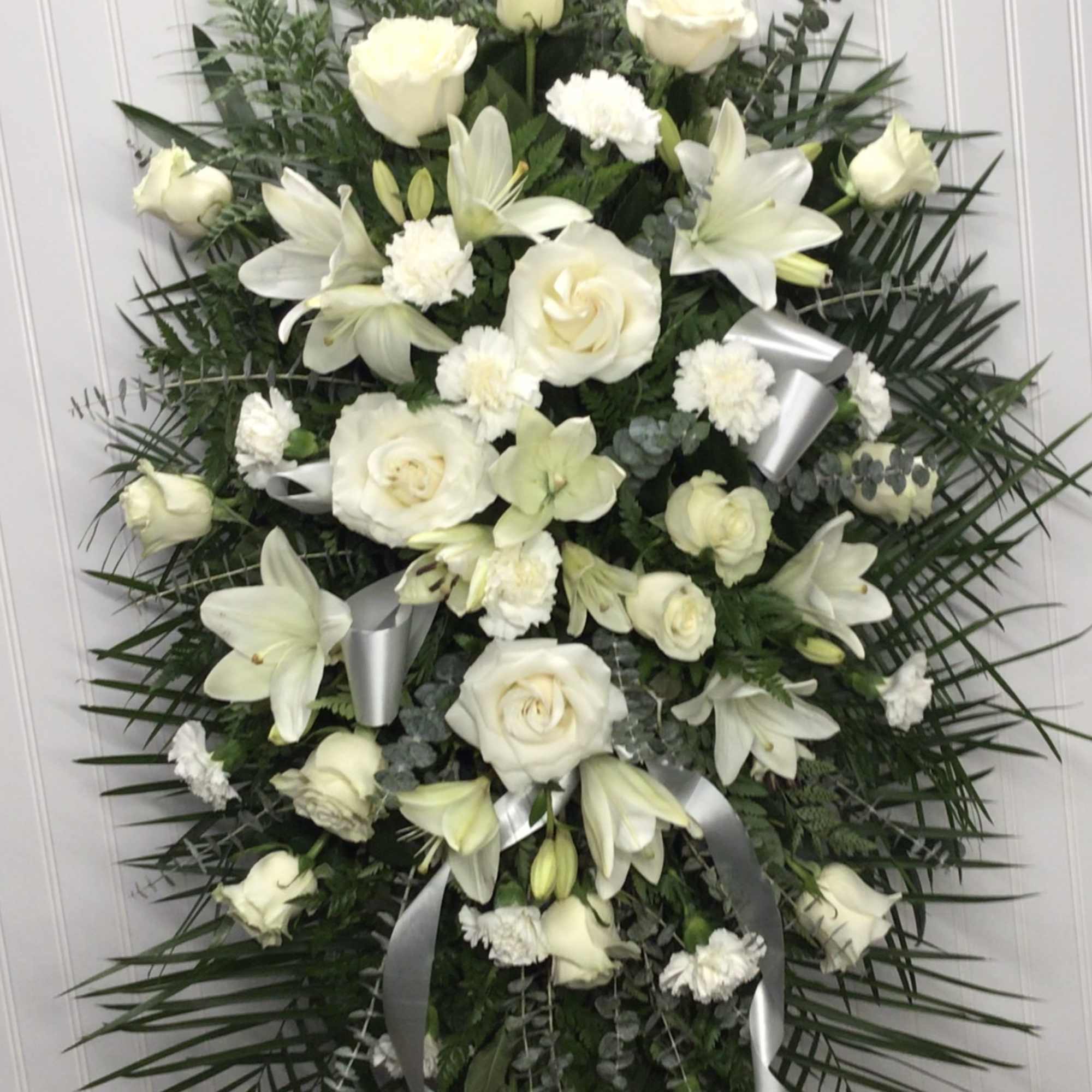 Beautifully simple this lovely spray of white roses lilies and carnations decorated