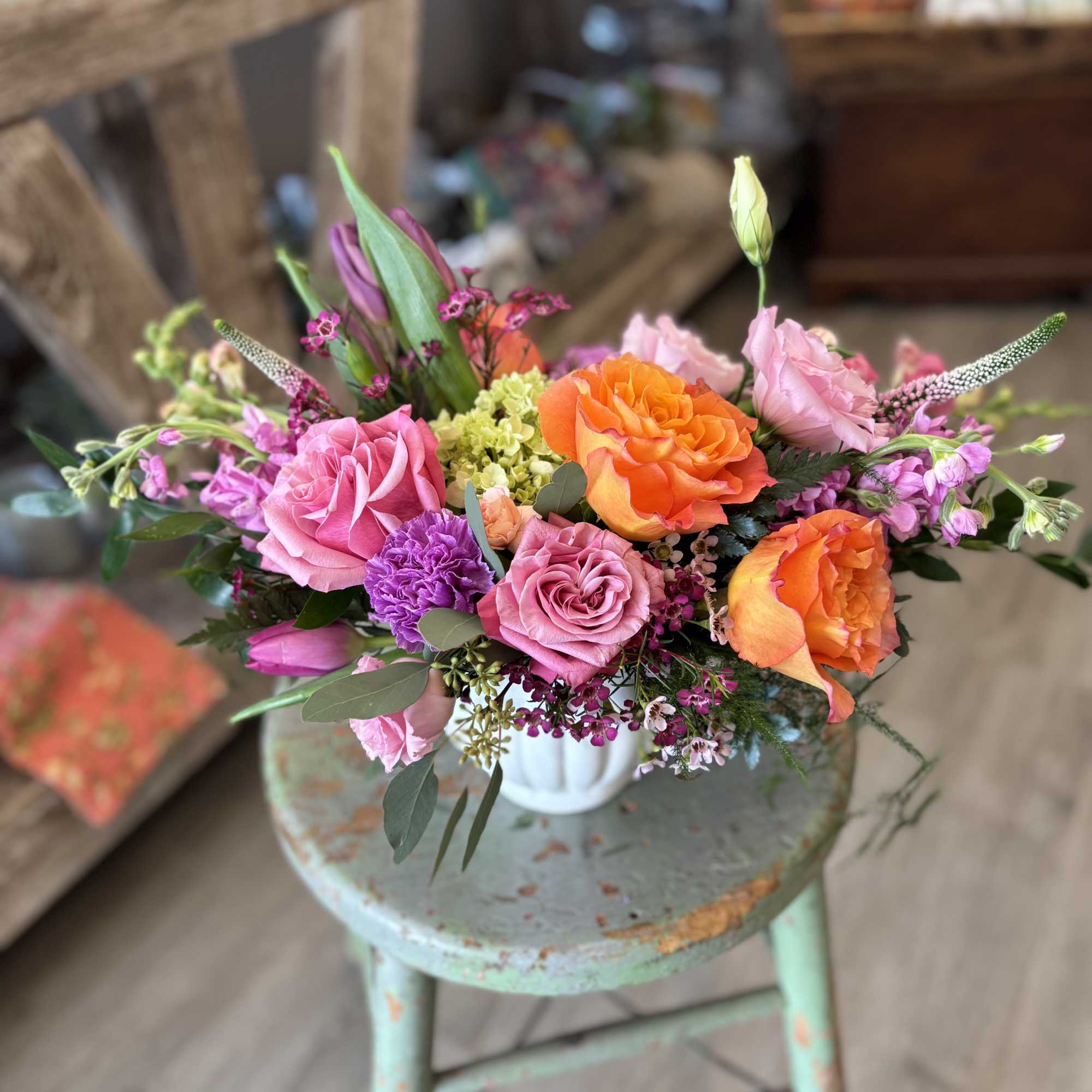 This joyful garden-style arrangement is filled with vibrant coral roses, fragrant lilac*