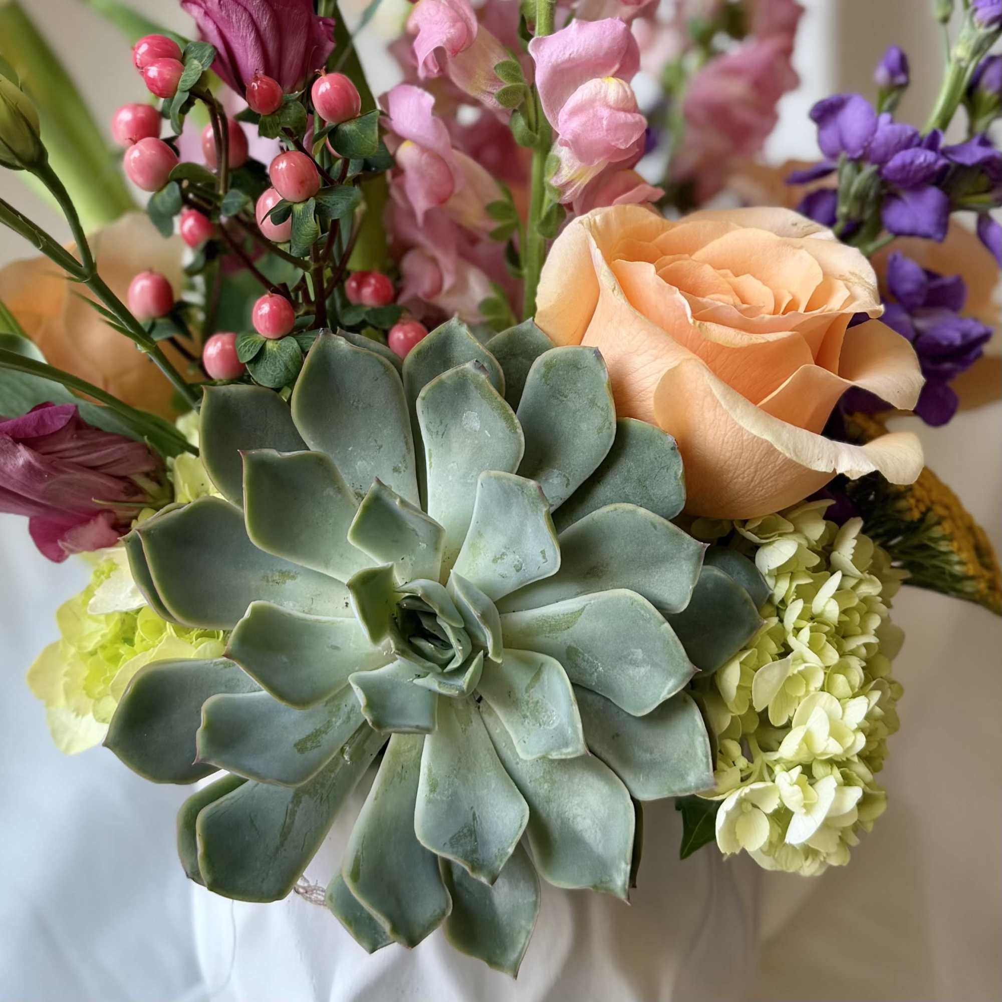 Bouquet with a peach rose, succulents, and pink and purple flowers