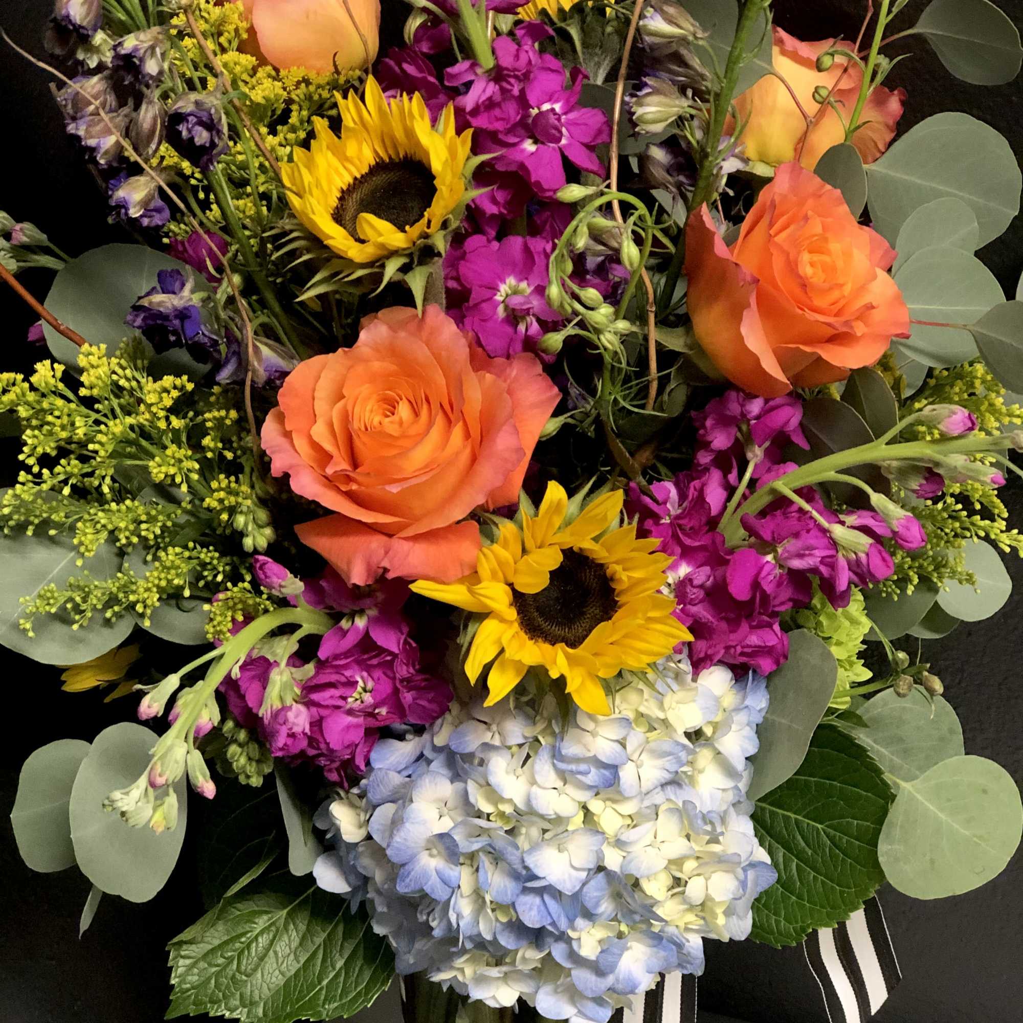 A bright elegant garden of Sunflowers, Hydrangea, Stock, Roses, and seasonal foliage.