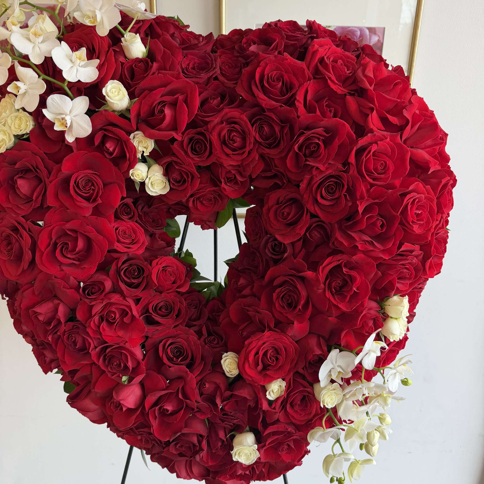 This heart funeral wreath features roses, mini phalaenopsis orchids 