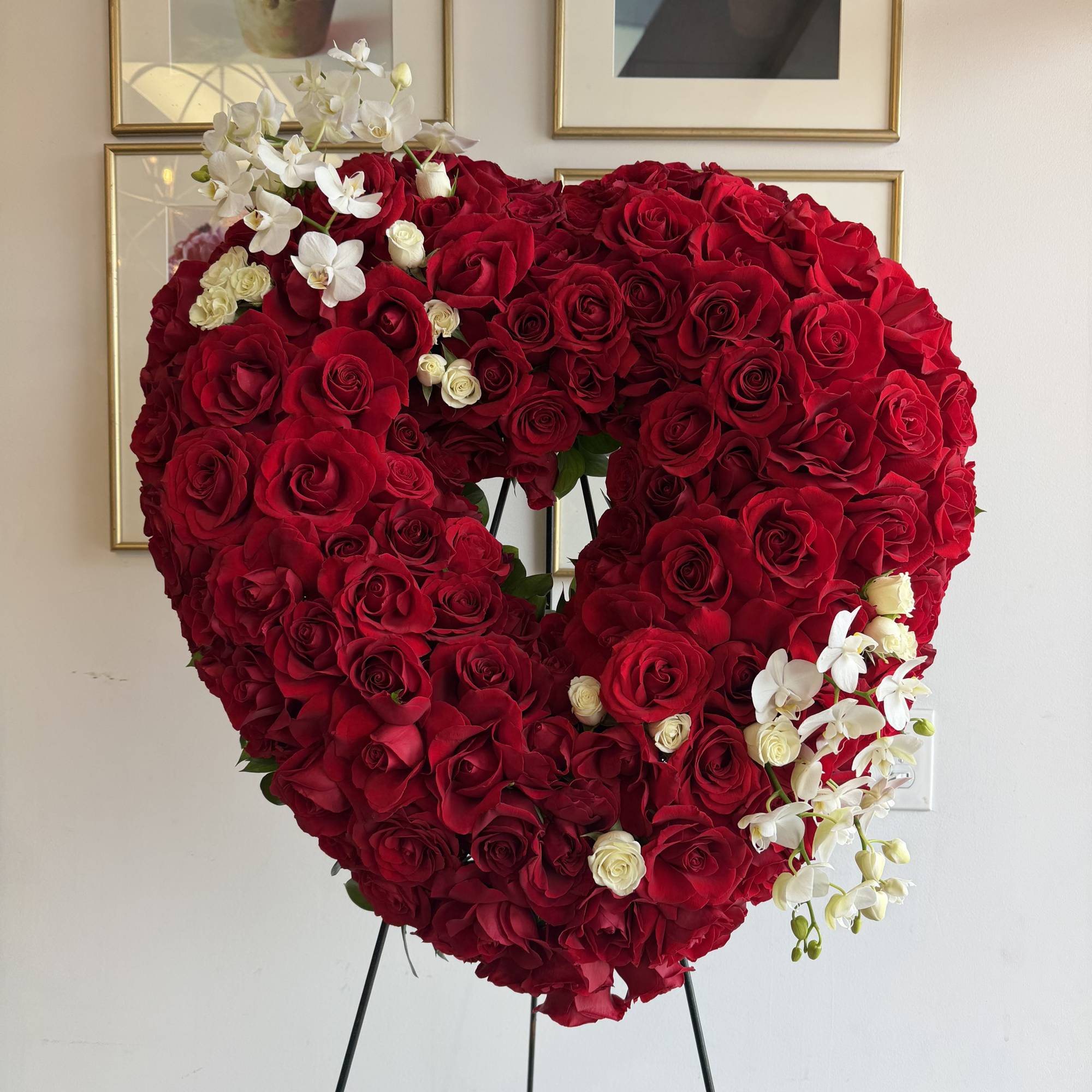 This heart funeral wreath features roses, mini phalaenopsis orchids 