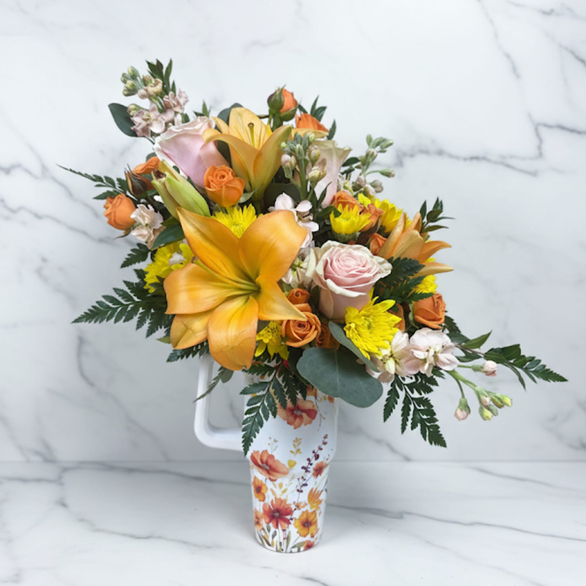Bouquet of orange lilies, roses, and yellow mums in a floral pitcher vase