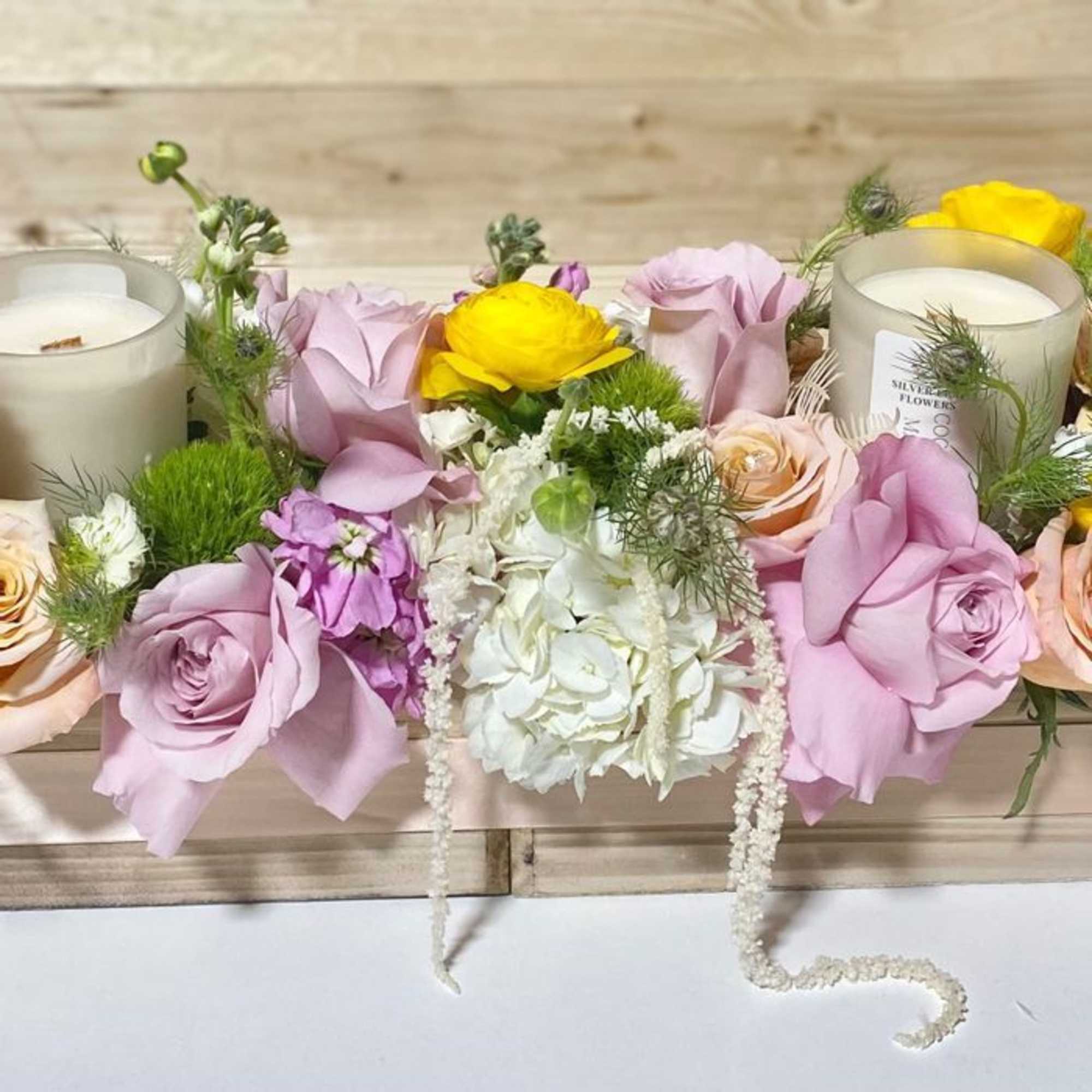Pastel floral arrangement with roses, hydrangea, and candles