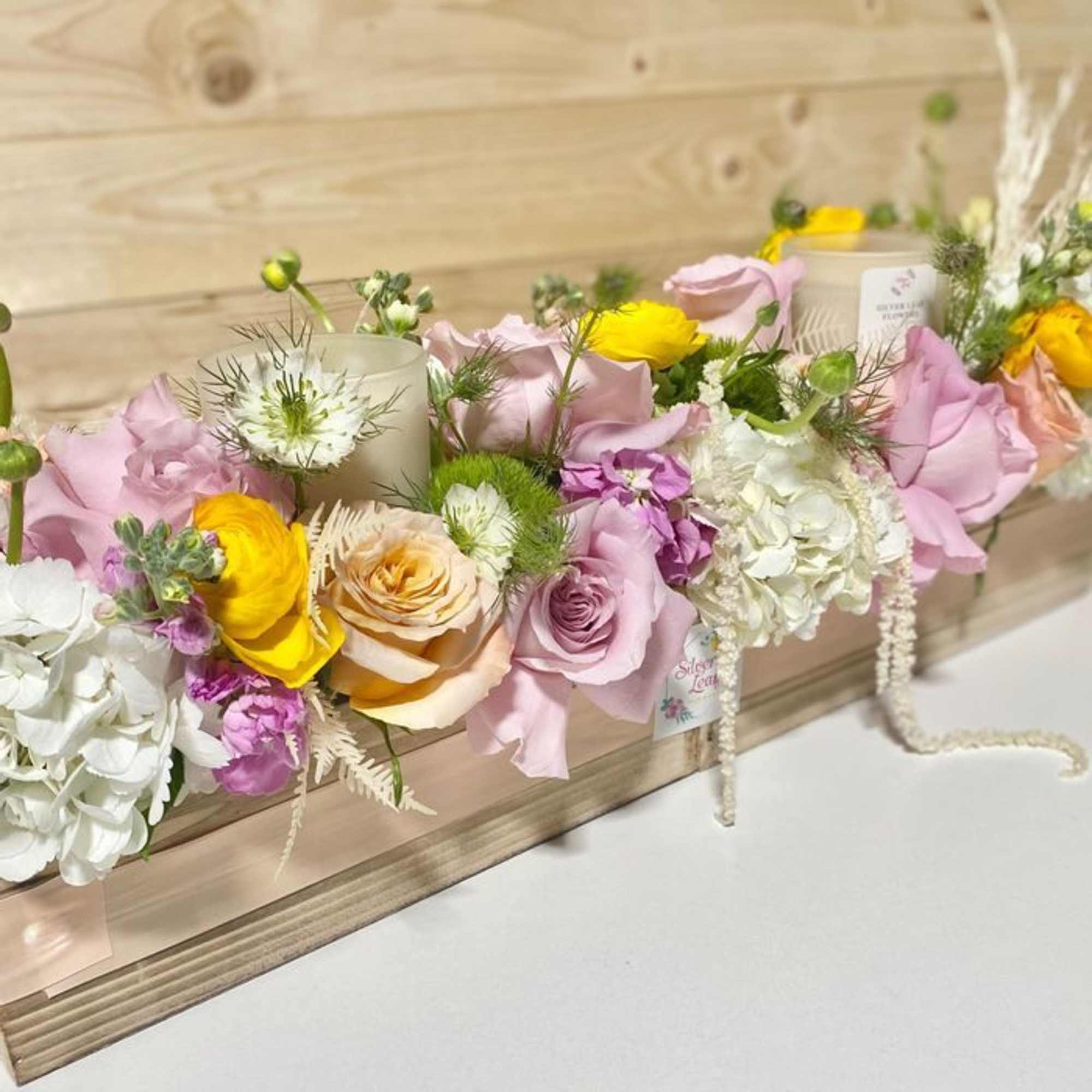 Pastel floral crown with pink, yellow, and white blooms on a wooden surface