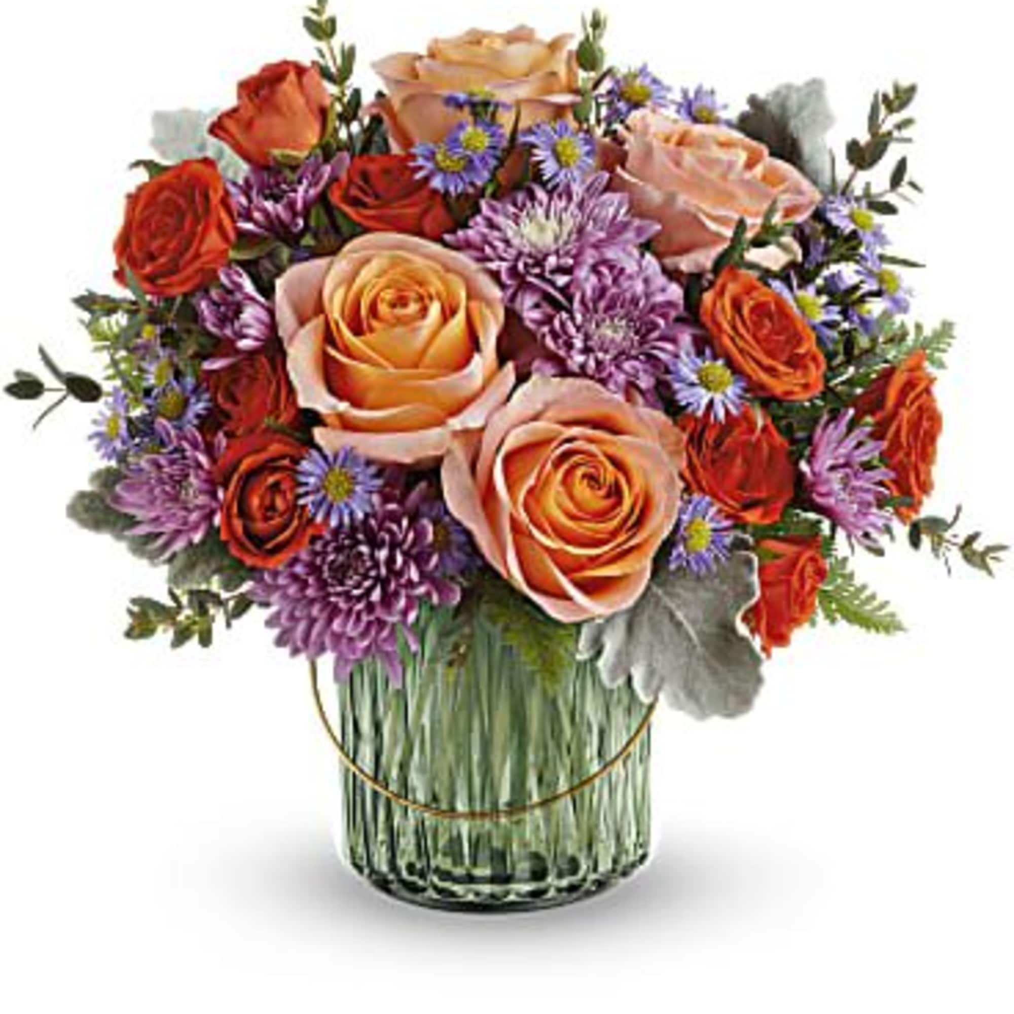 Bouquet of peach and orange roses with purple daisies in a glass vase