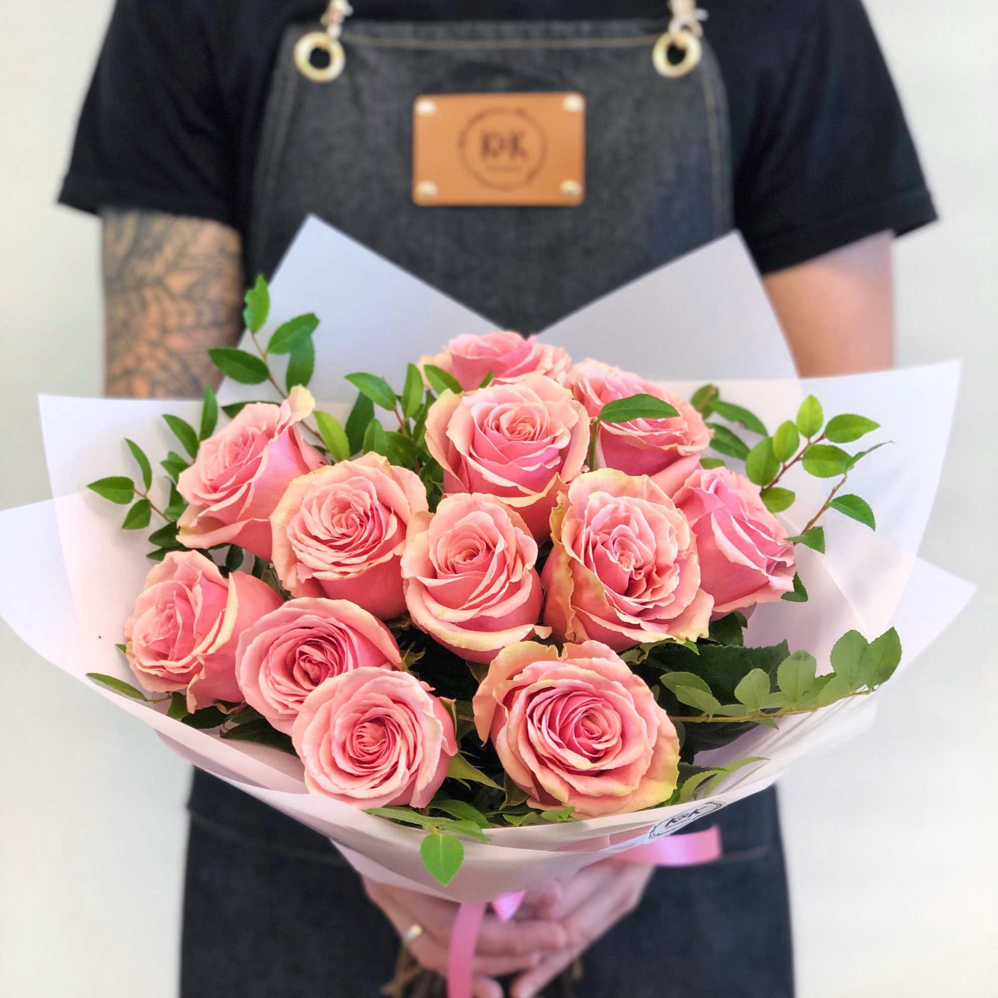 Dozen Pink Roses with greenery and decorative wrapping paper. All bouquets come