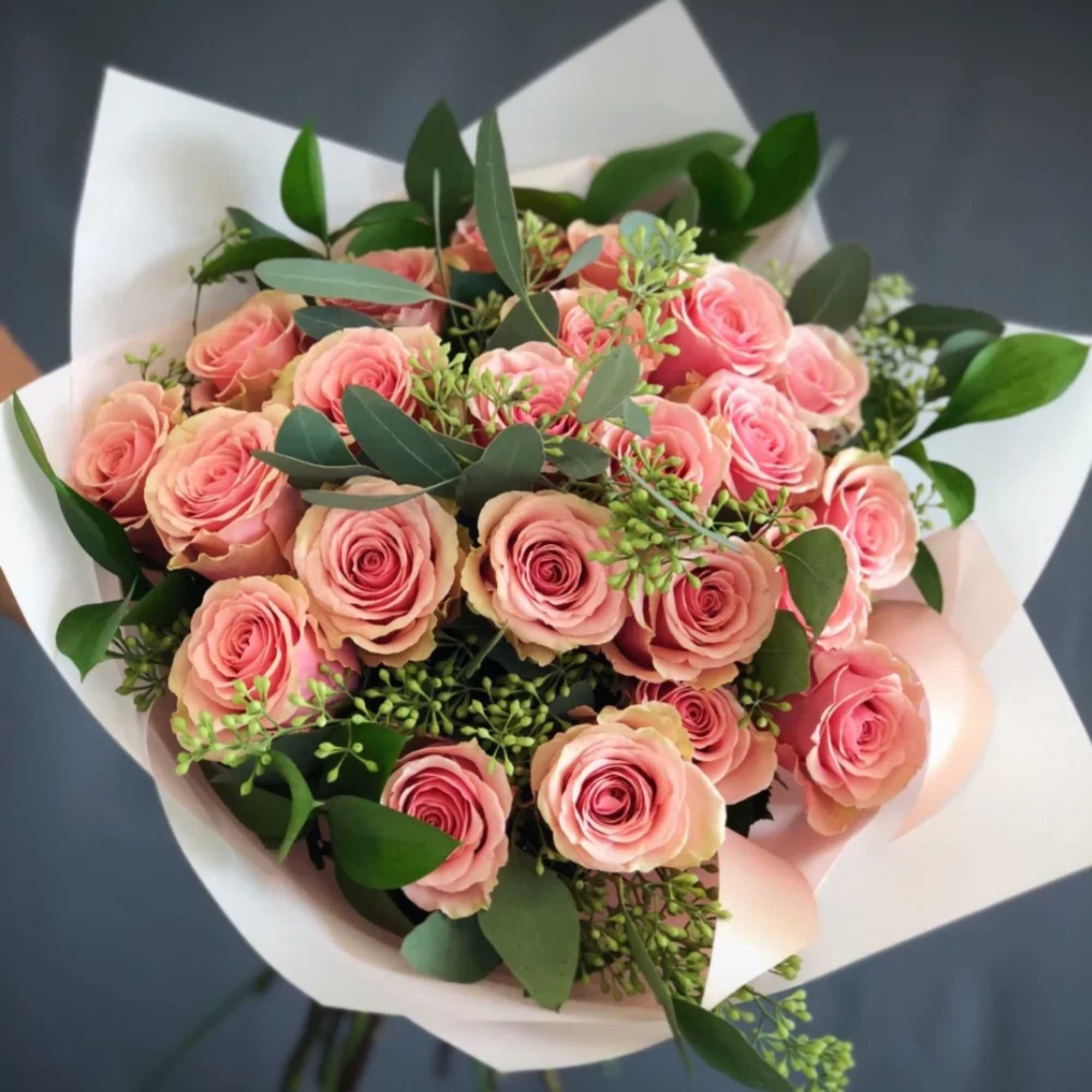 Dozen Pink Roses with greenery and decorative wrapping paper. All bouquets come