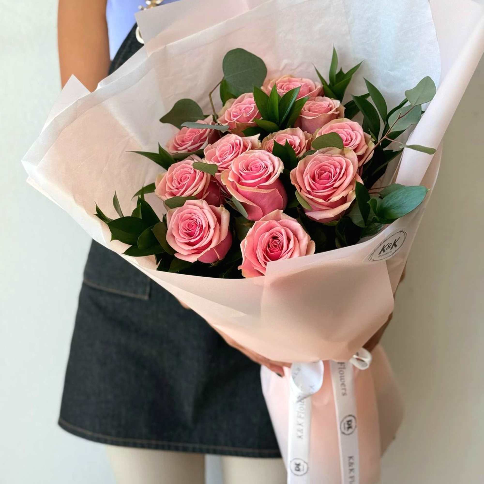 Dozen Pink Roses with greenery and decorative wrapping paper. All bouquets come