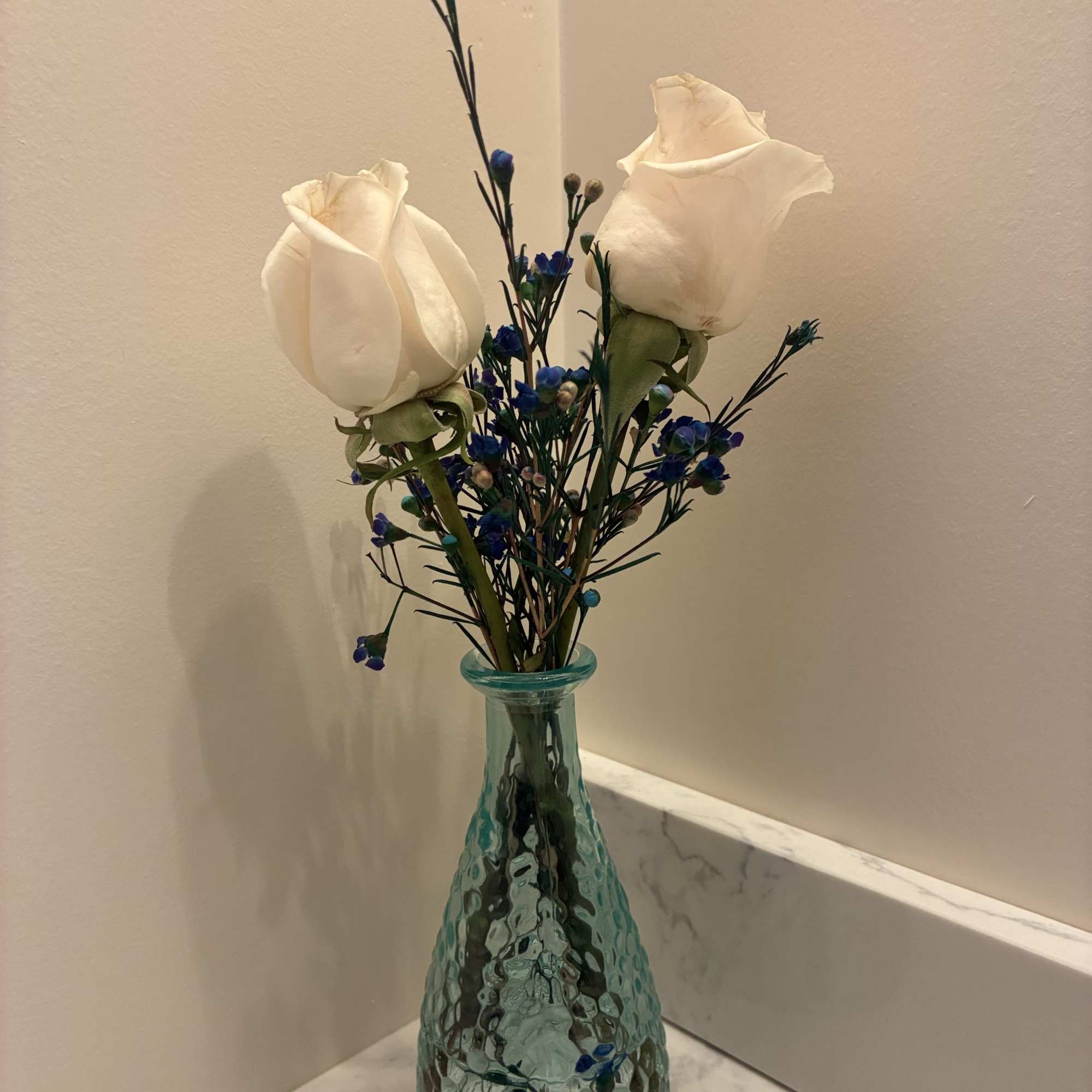 Two beautiful roses arranged with fresh greenery in a petite vase. This