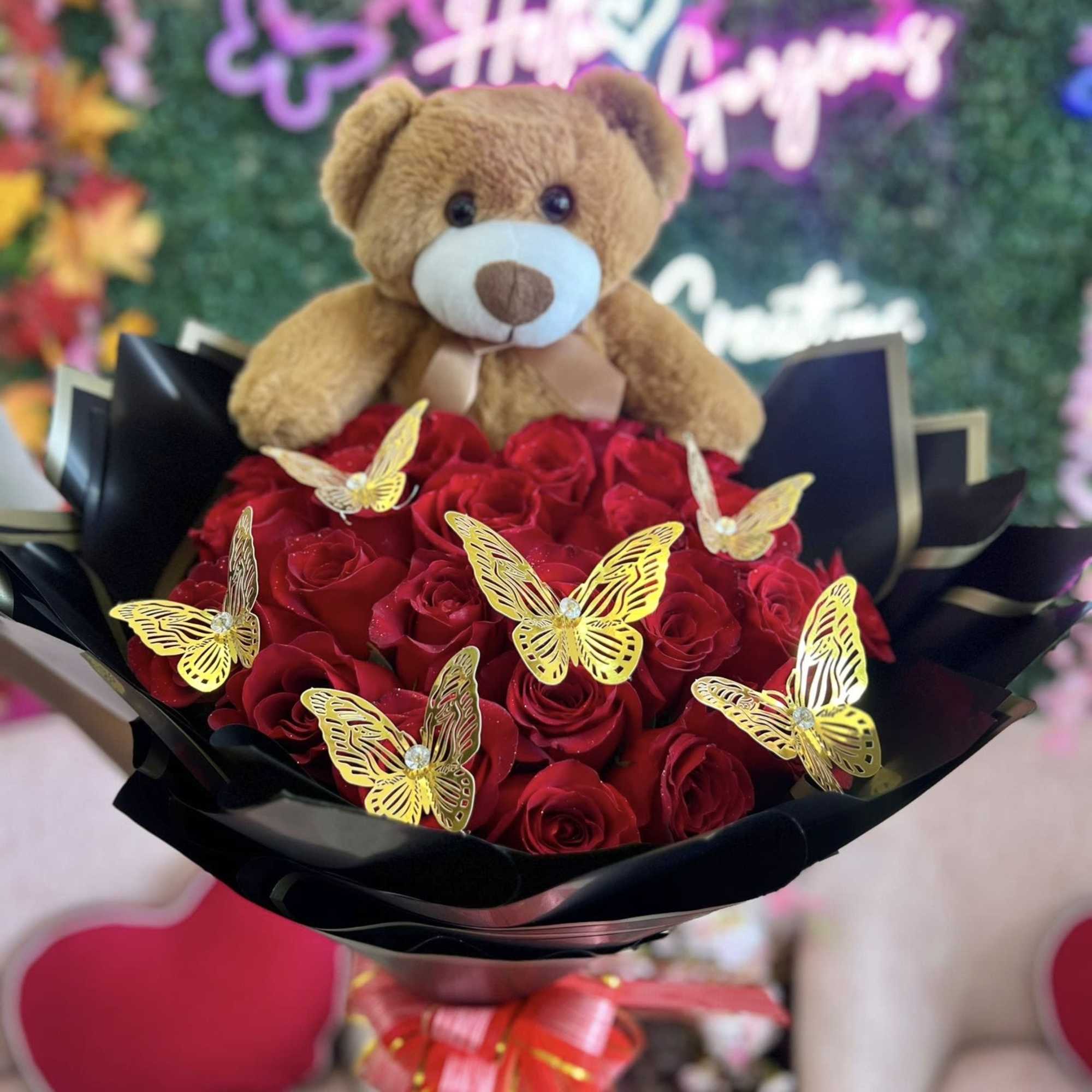 Red rose bouquet with a teddy bear and gold butterfly accents