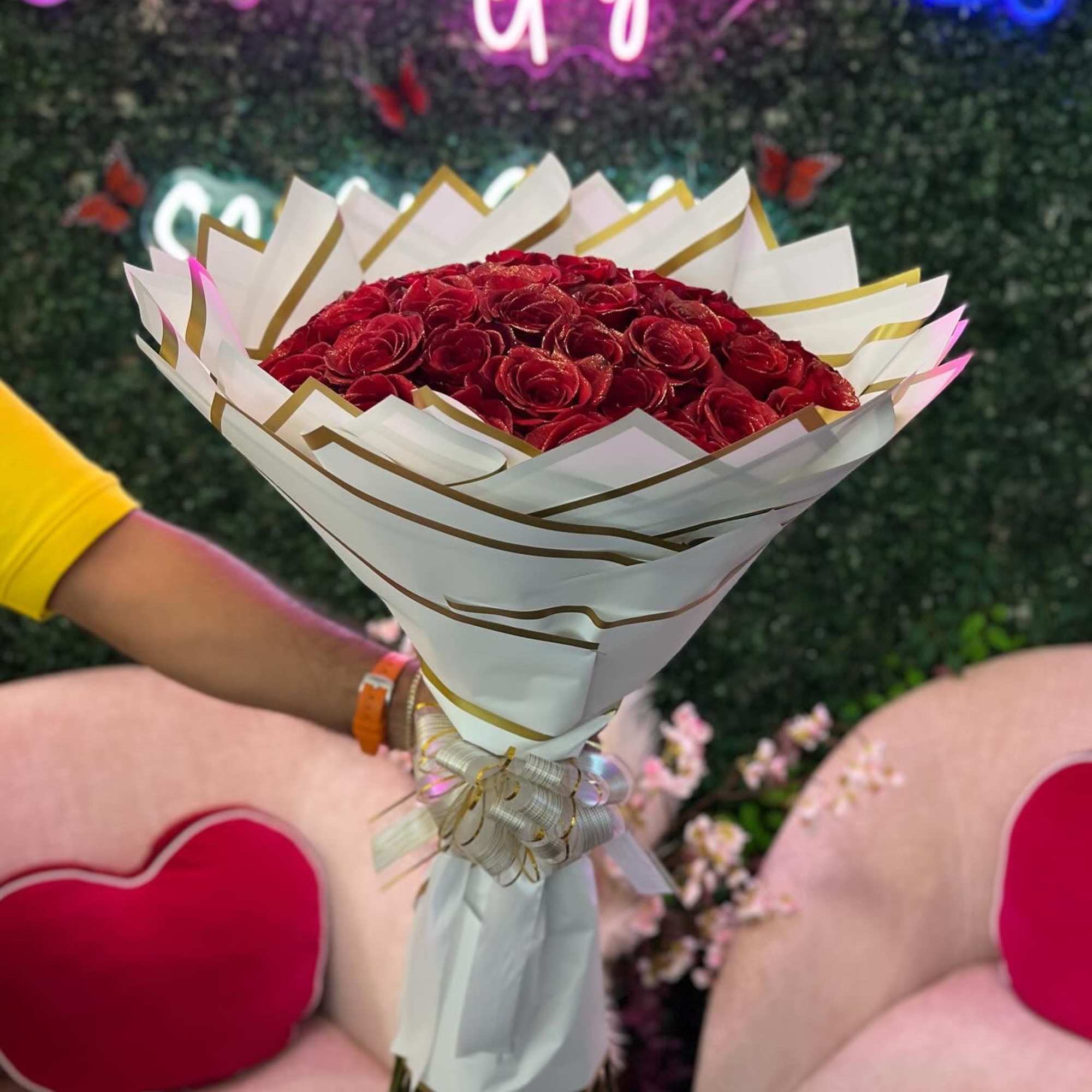 Bouquet of red roses wrapped in white paper with gold trim