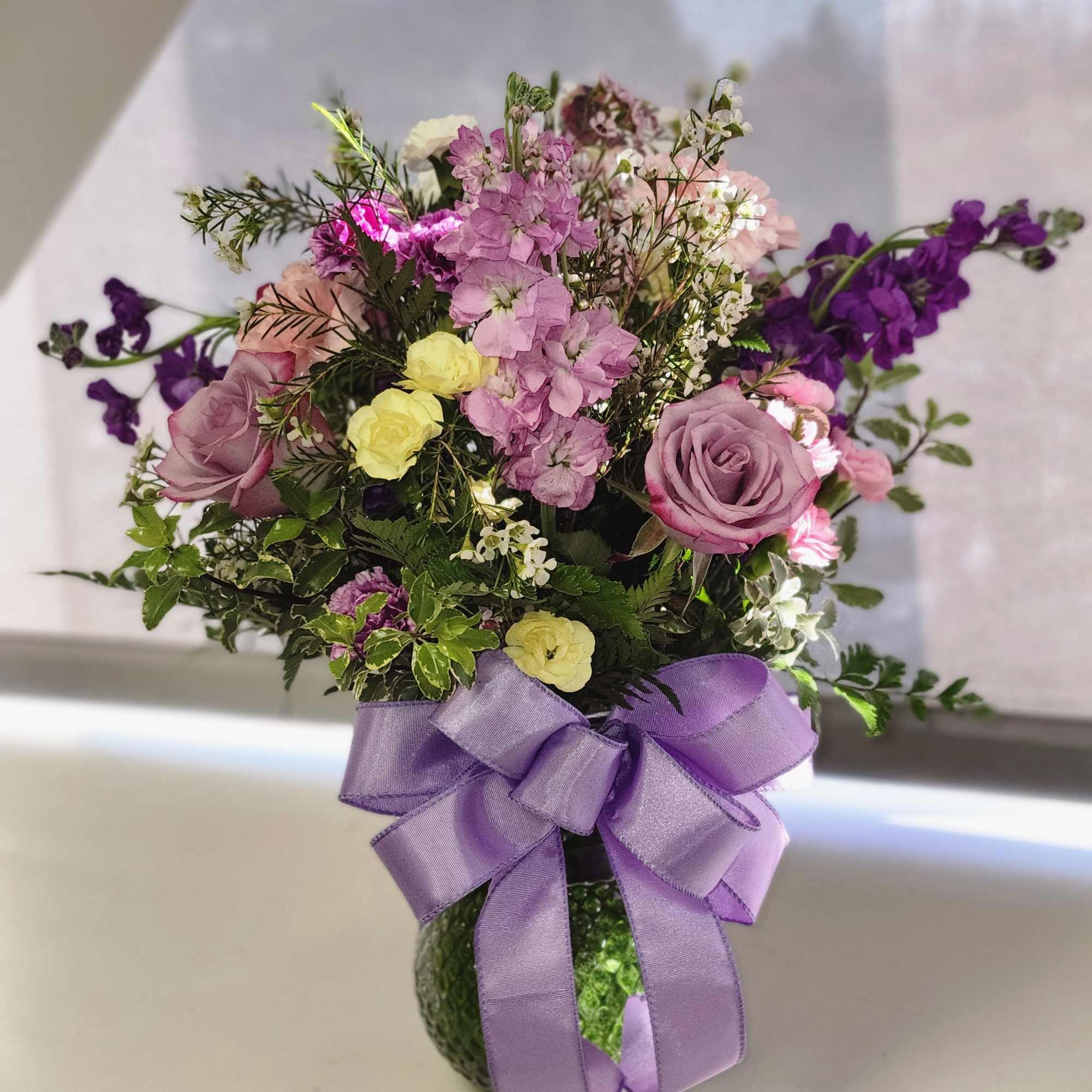 Colors of purple, lavender, yellow and white. Combination of Roses, stock and