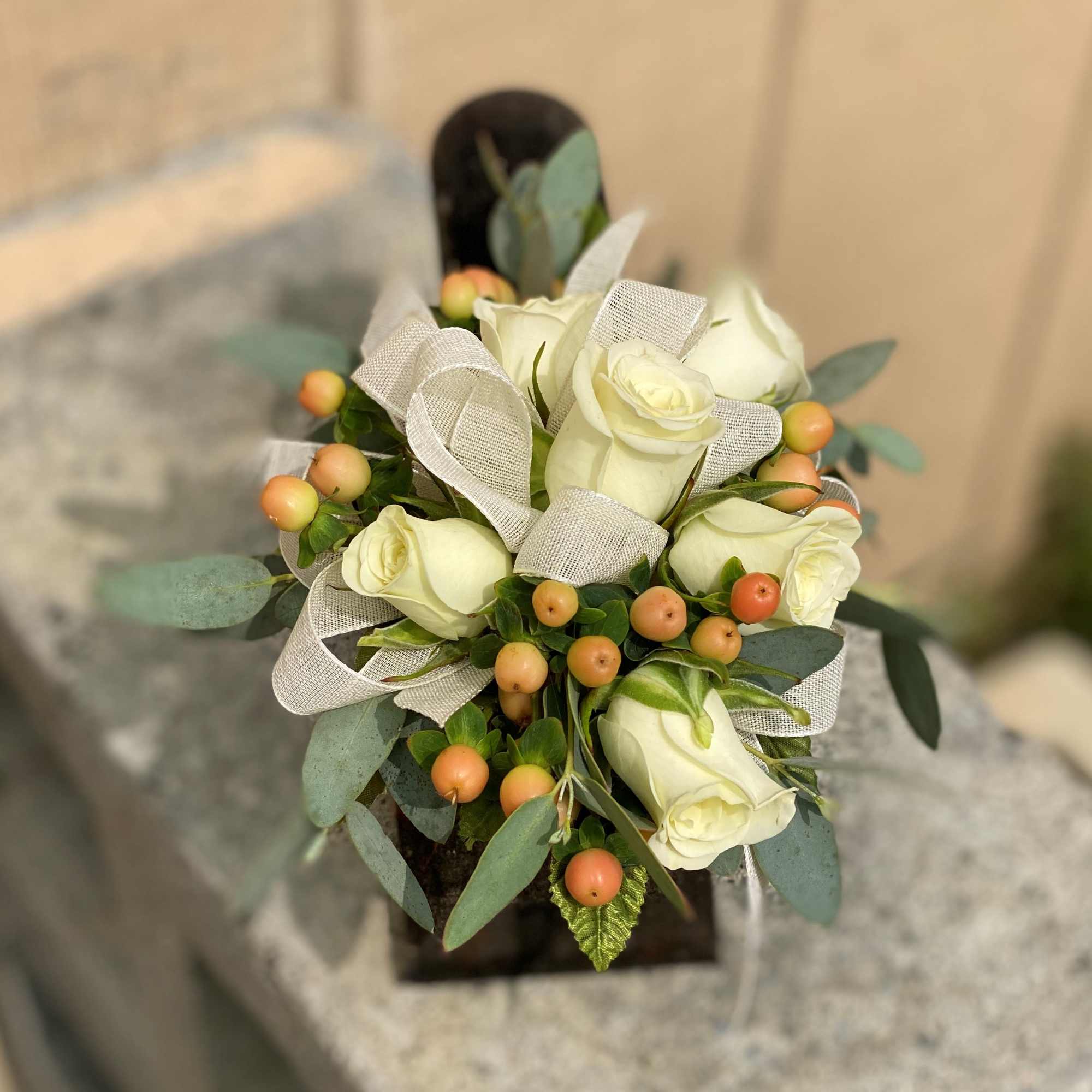 This wrist corsage is made up of white spray roses, peach hypericum