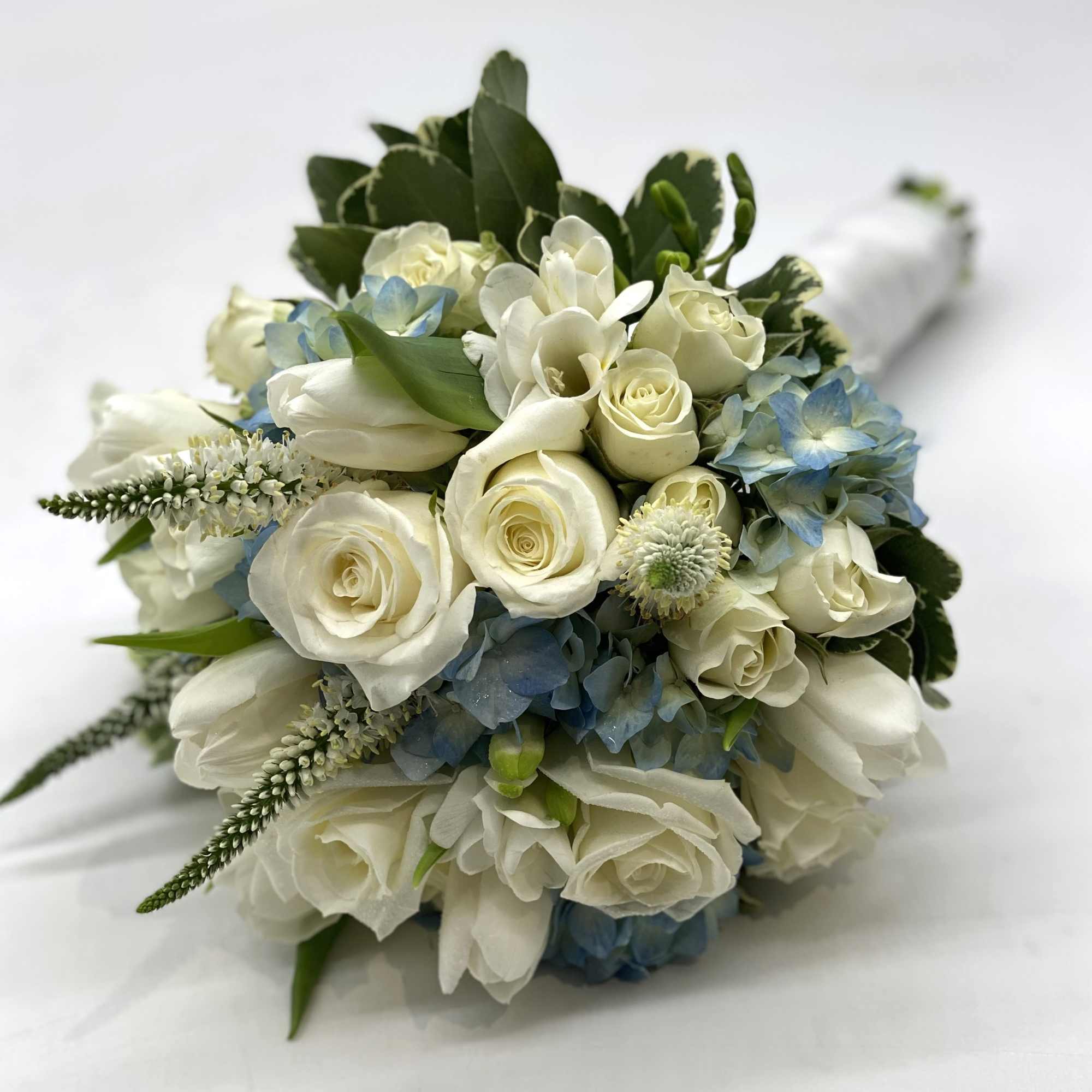 A lush mix of white flowers designed within a blue hydrangea. 