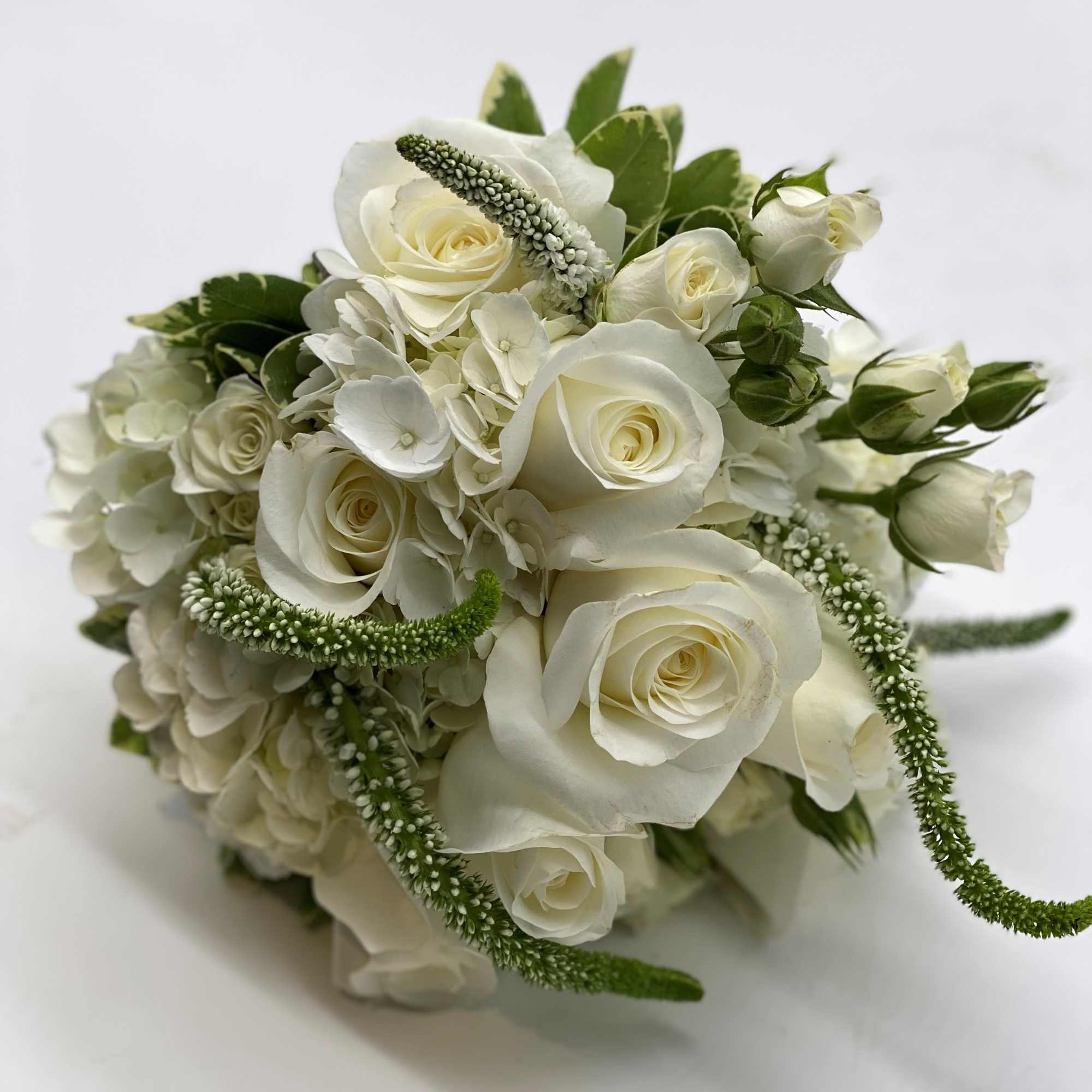 A lush mix of white flowers finished off with a white satin