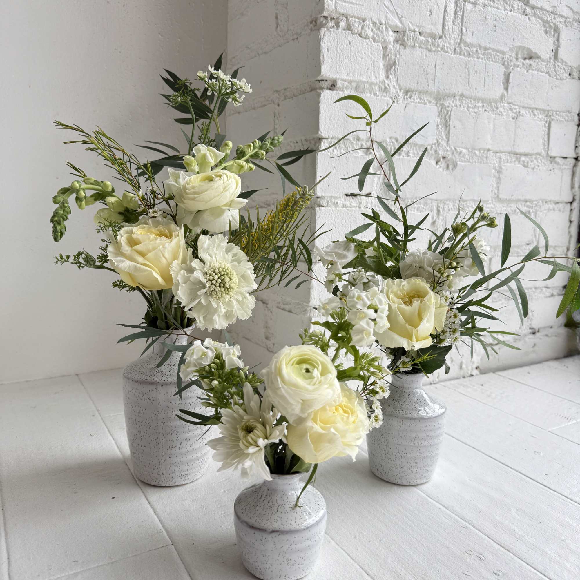 An eclectic mix of seasonal white flowers with foliage in a set