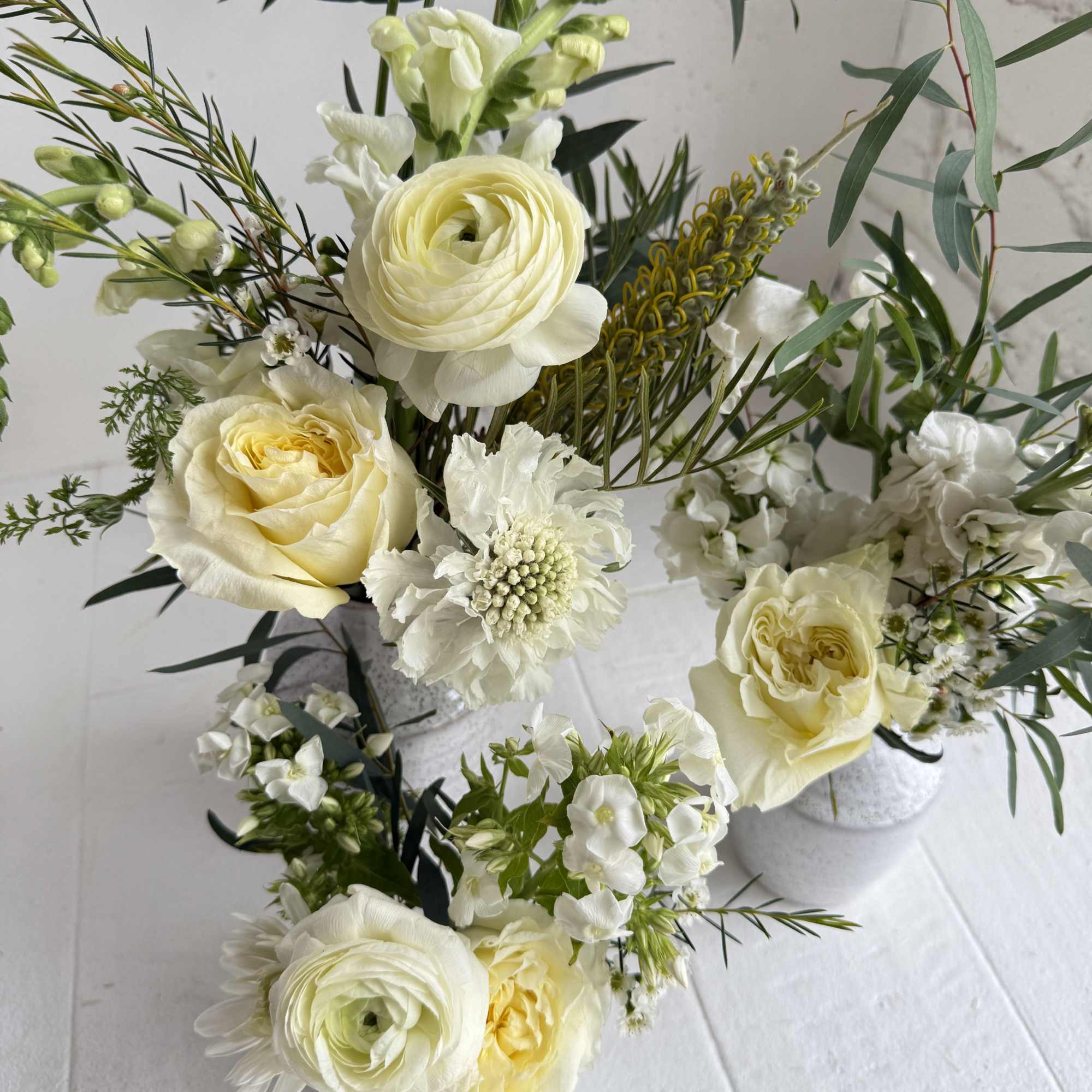 An eclectic mix of seasonal white flowers with foliage in a set