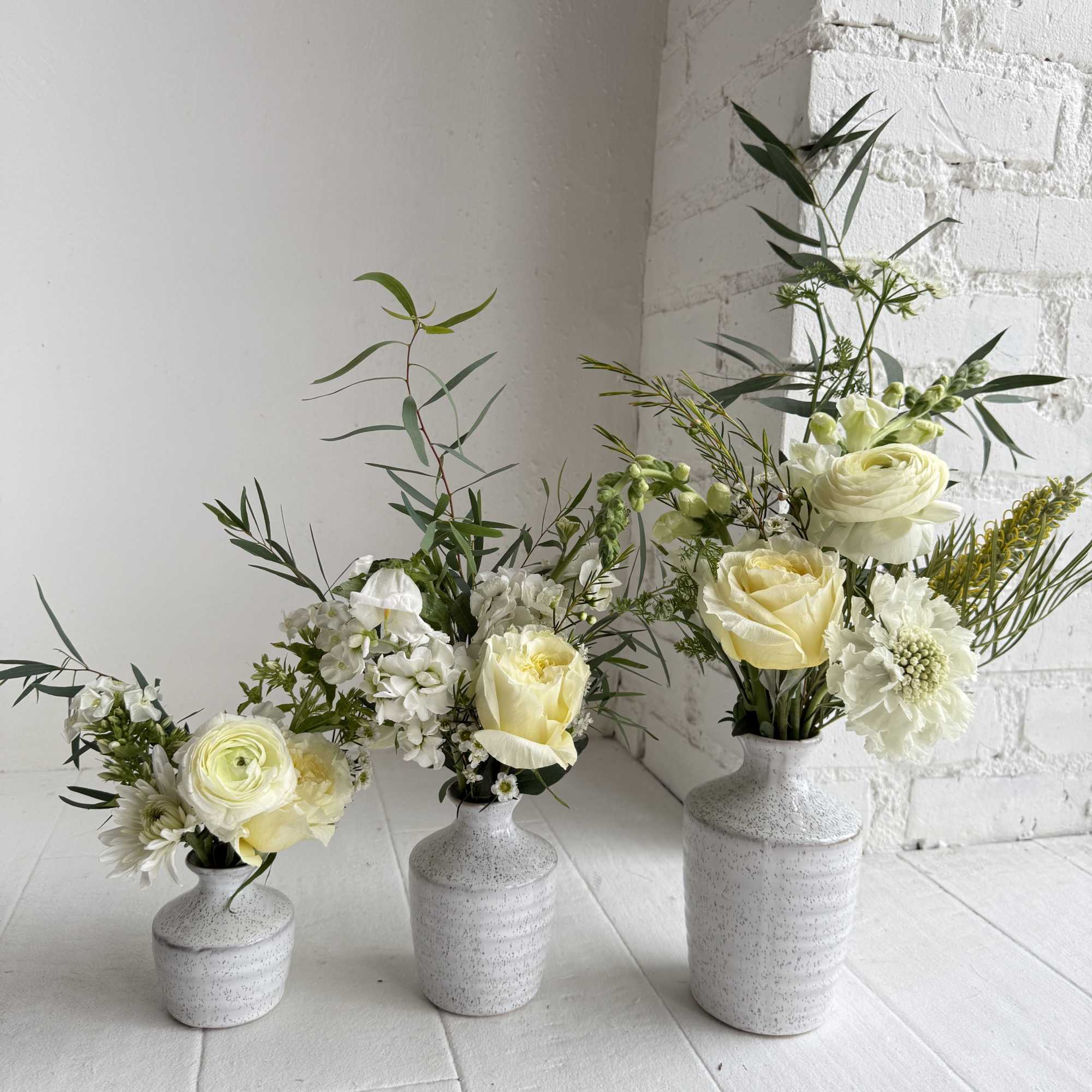An eclectic mix of seasonal white flowers with foliage in a set