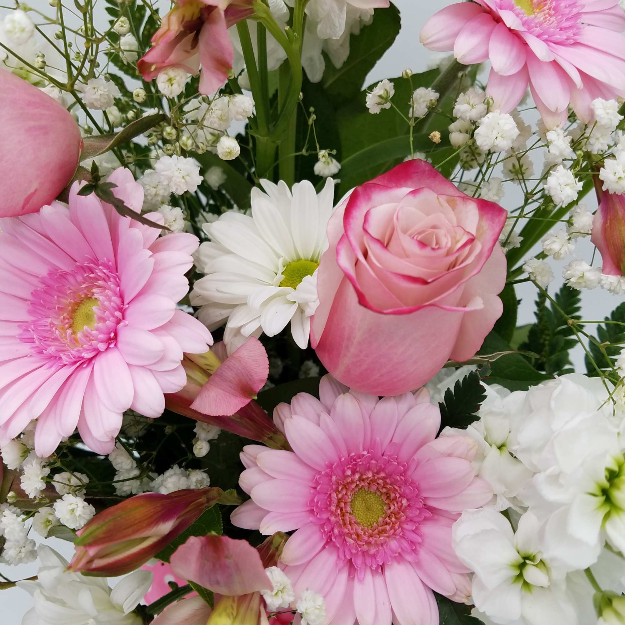 Bouquet of pink gerbera daisies, pink roses, white daisies, and baby’s breath in a mixed arrangement