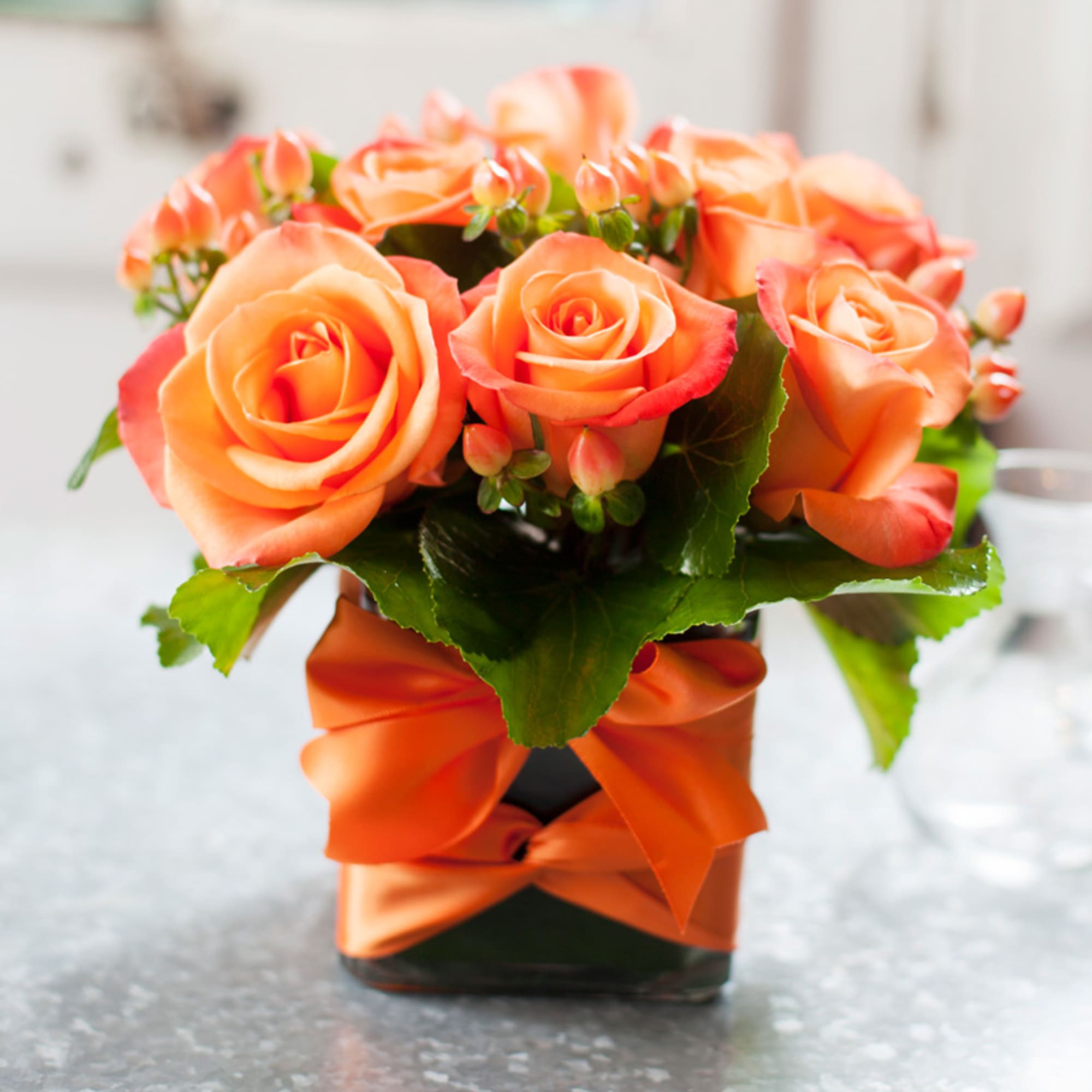 Orange roses mixed with hypericum in a simple cube
also: available in red