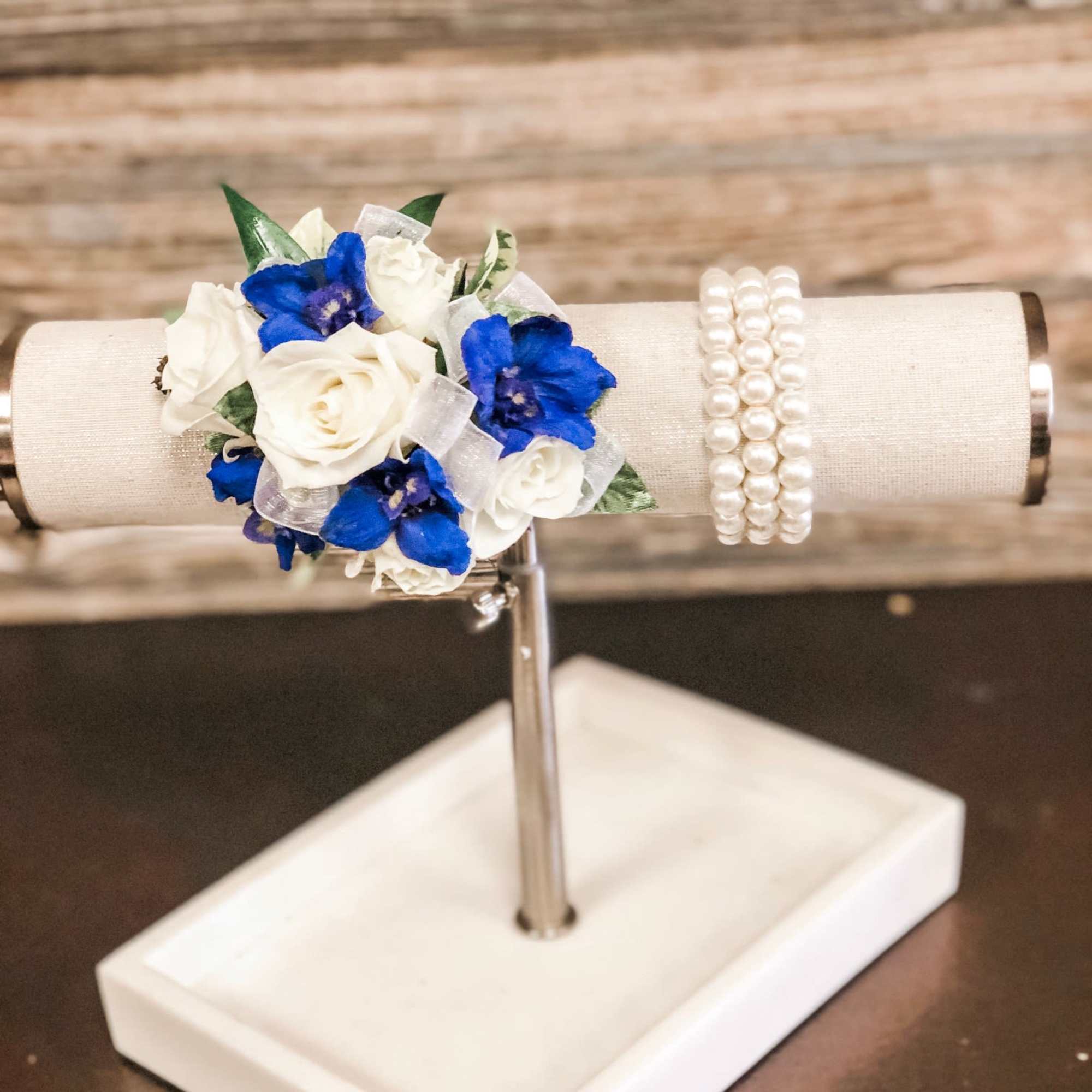White spray roses, sheer ribbon, blue delphinium on a bed of greenery.