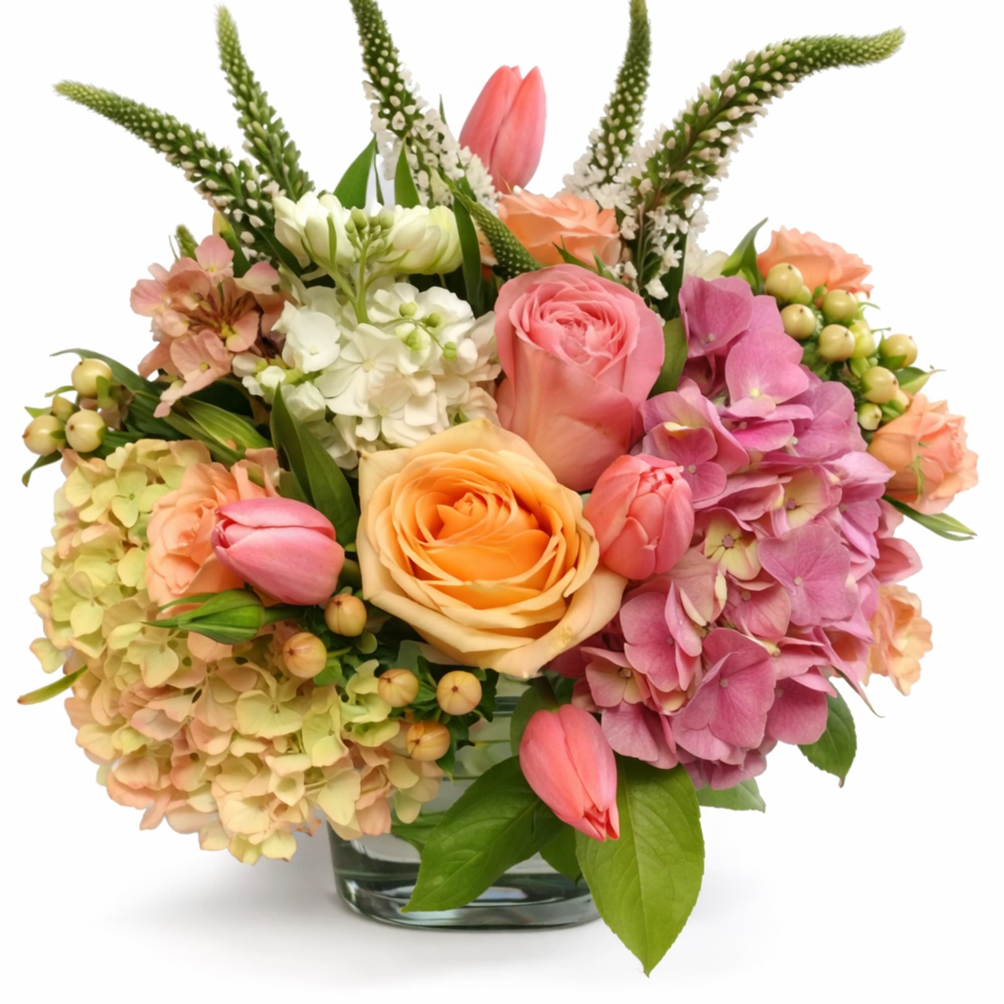Mixed bouquet of roses, hydrangeas, and tulips in a glass vase