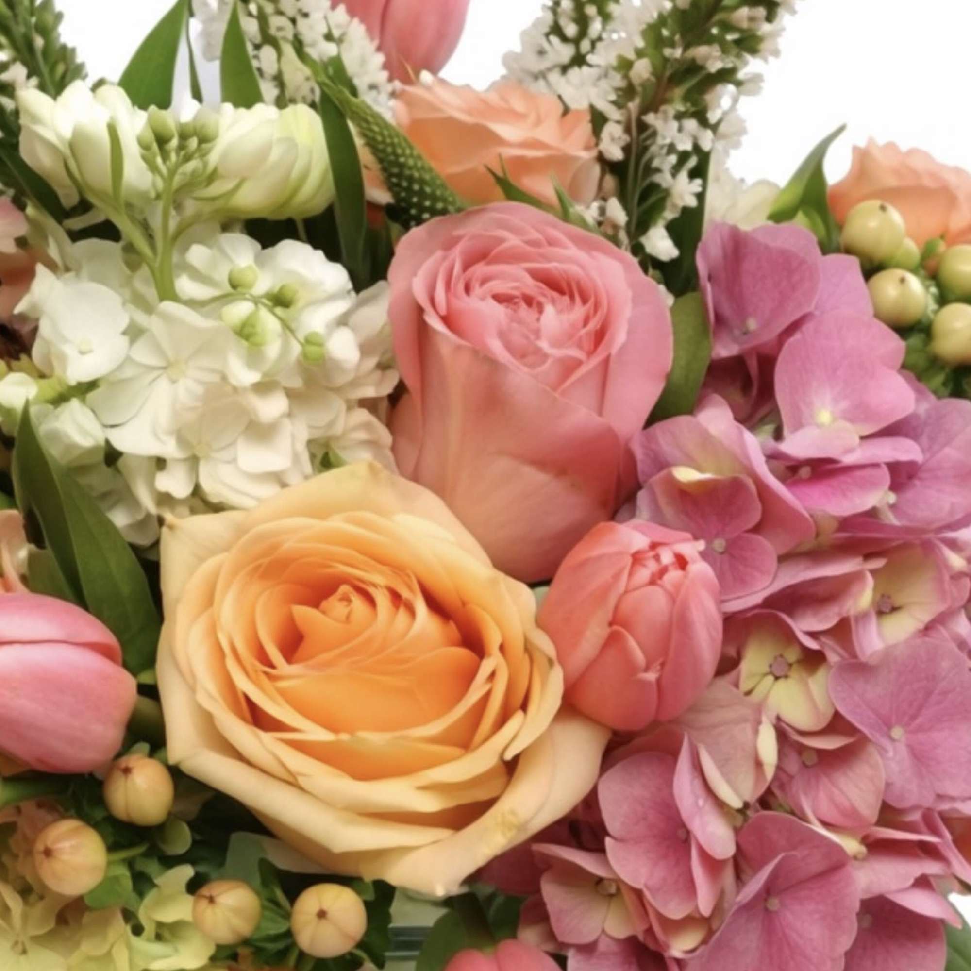 Mixed bouquet with roses, tulips, and hydrangeas in a glass vase