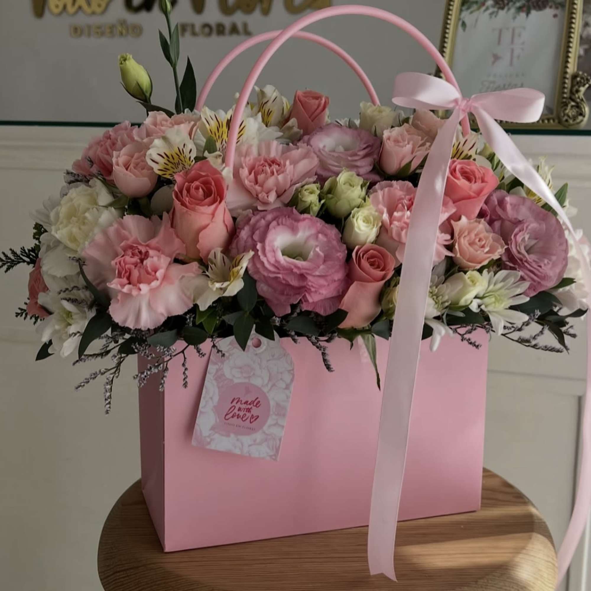 Pink floral arrangement in a pink gift bag with ribbon handles